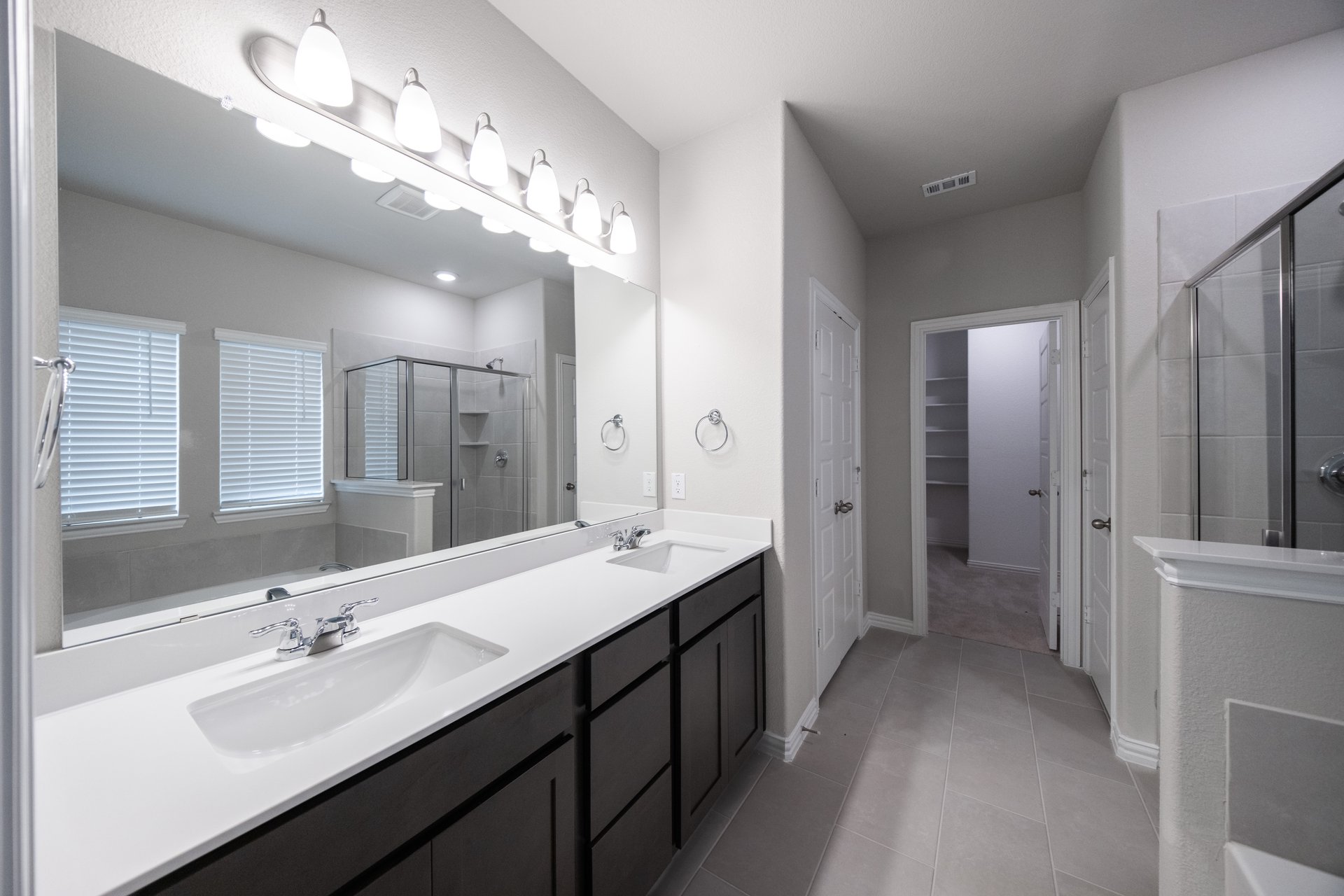 primary bathroom with two sinks and dark cabinets