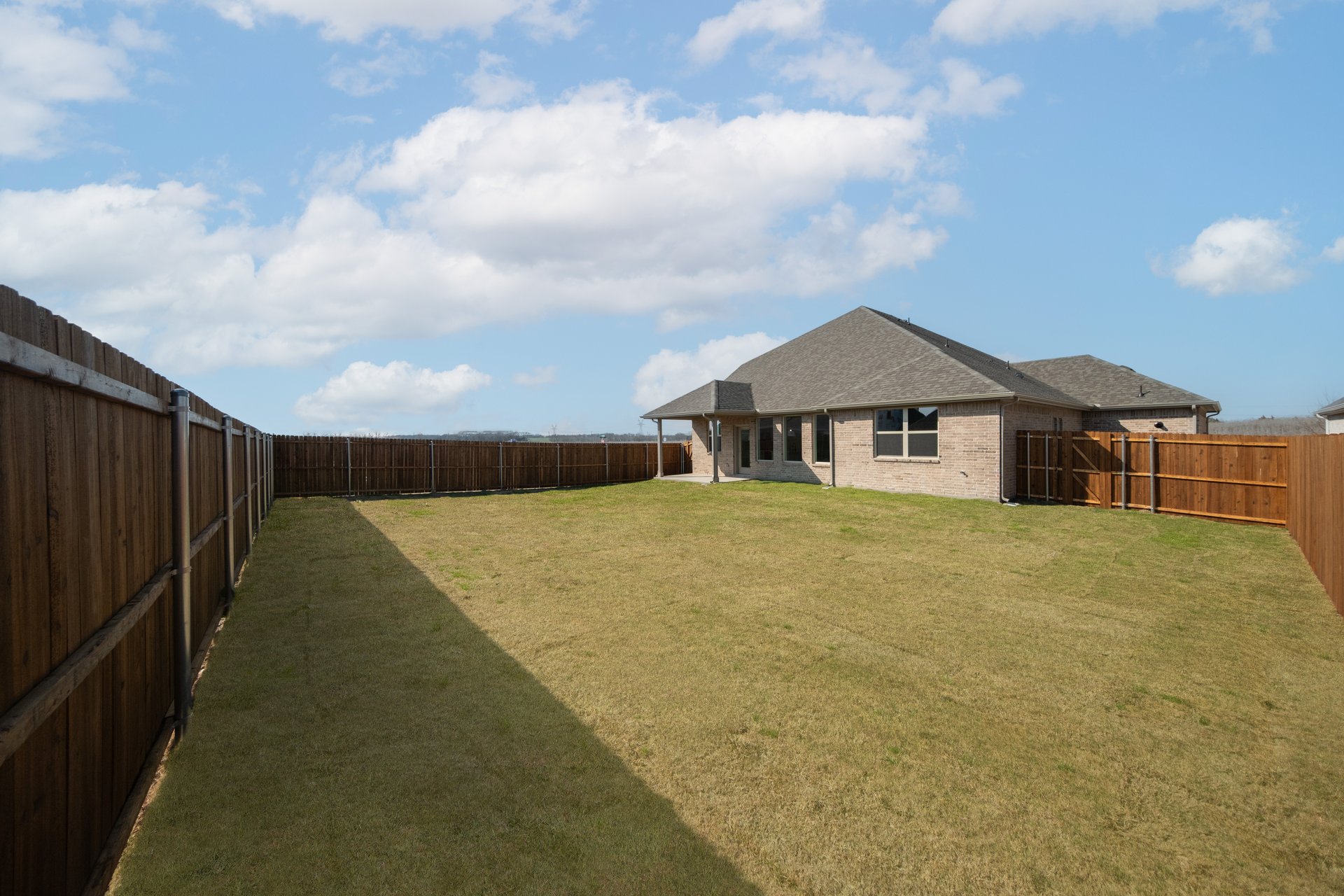 fenced in backyard of home with grass