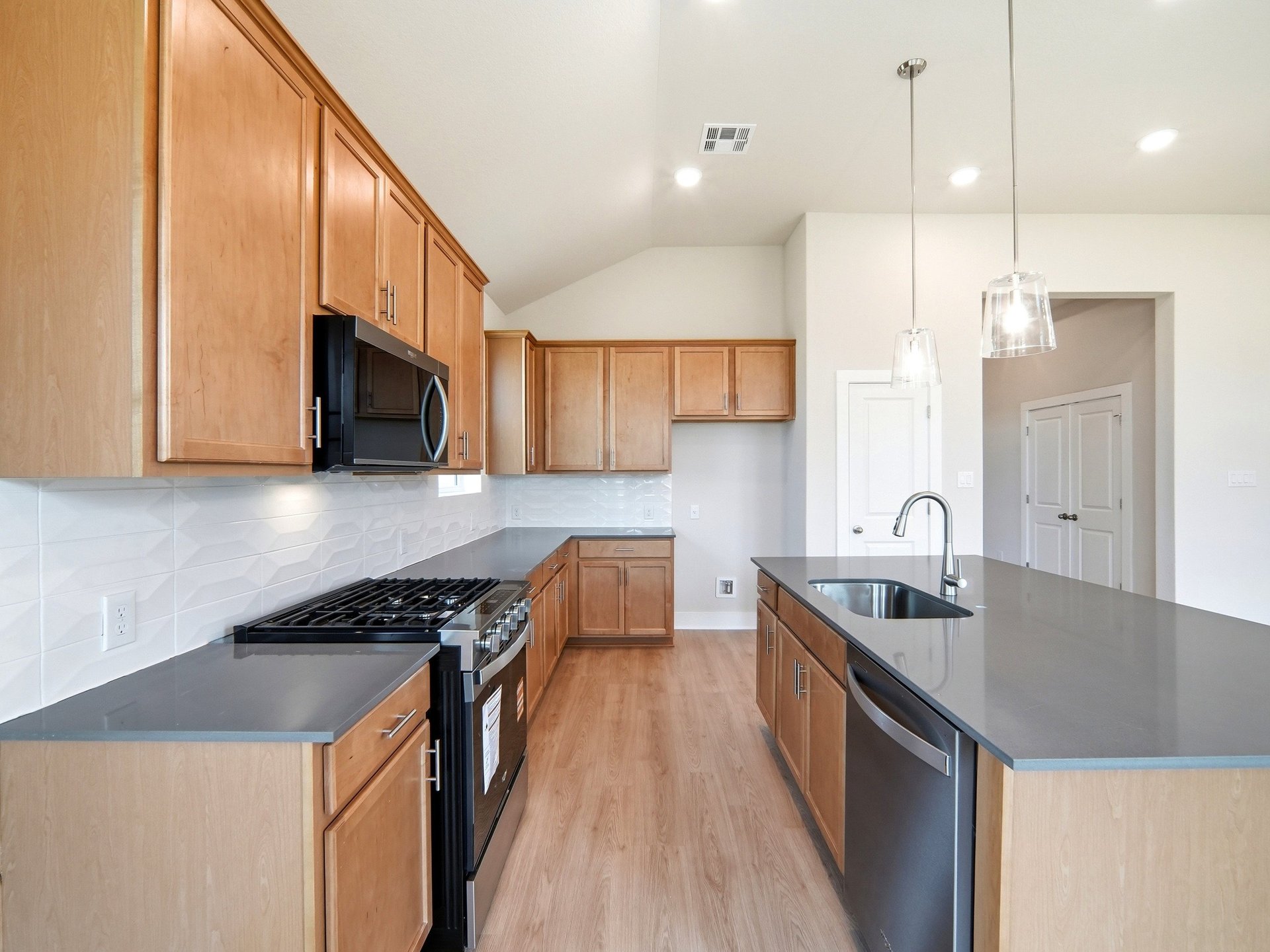 Kitchen with brown cabinets, quartz countertops and pendant lighting