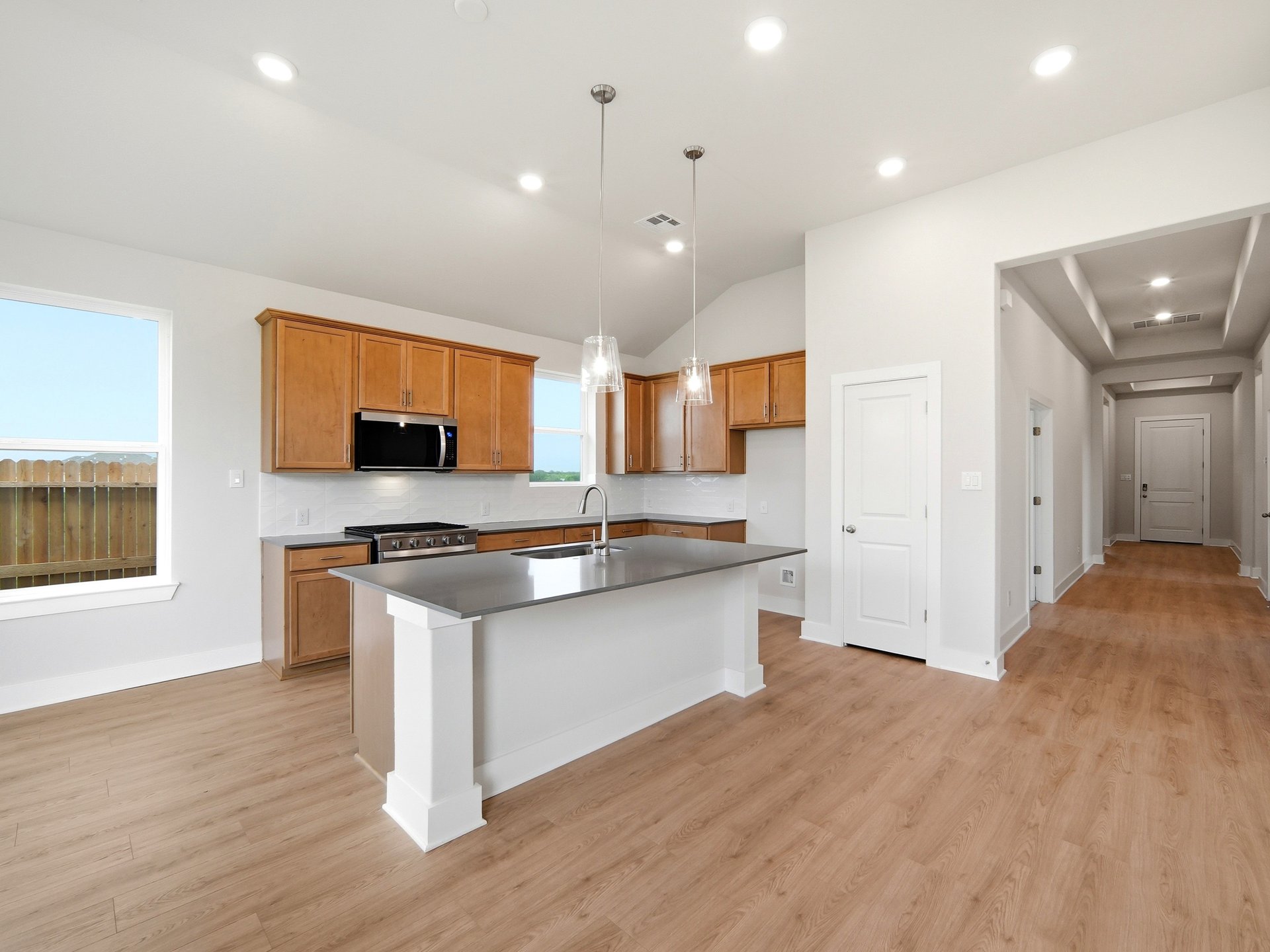 kitchen with brown cabinets, quartz countertops and pendant lighting