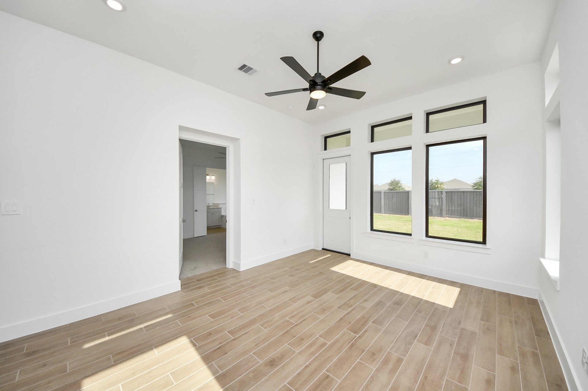 wood-like tile flooring and tall ceilings with fan