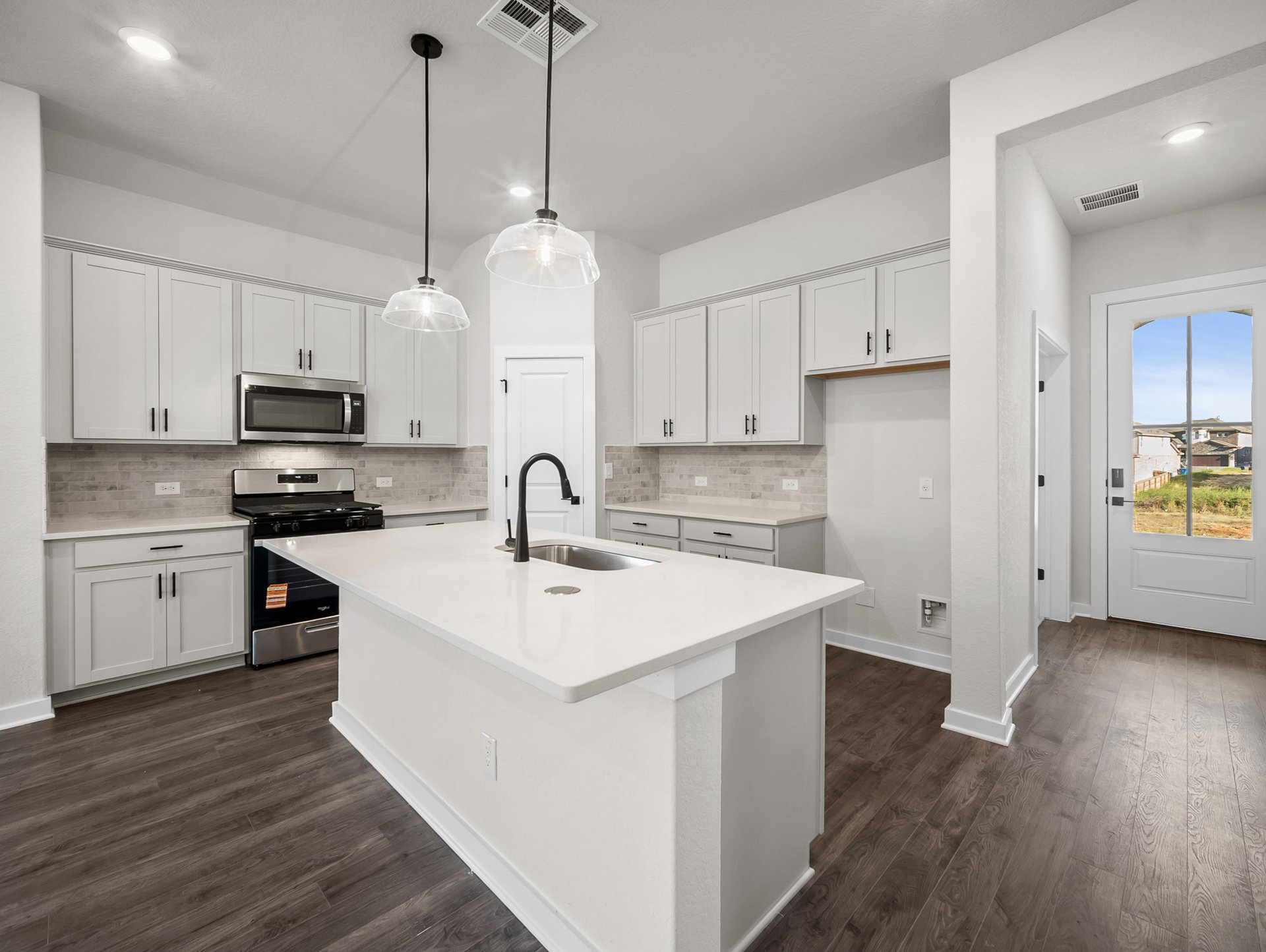 kitchen with quartz countertops, pendant lighting & white cabinets