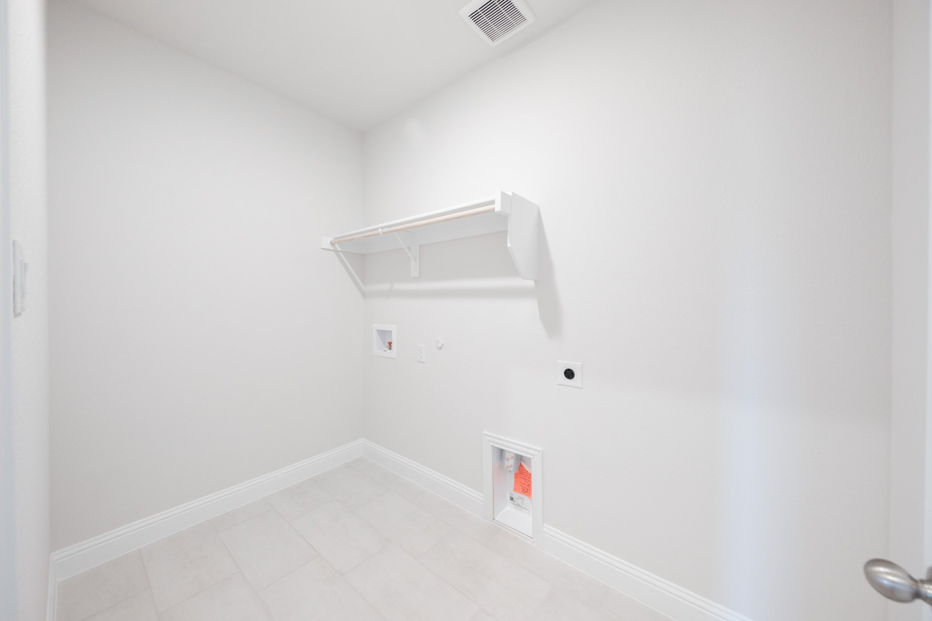 laundry room with tile floors and white shelf