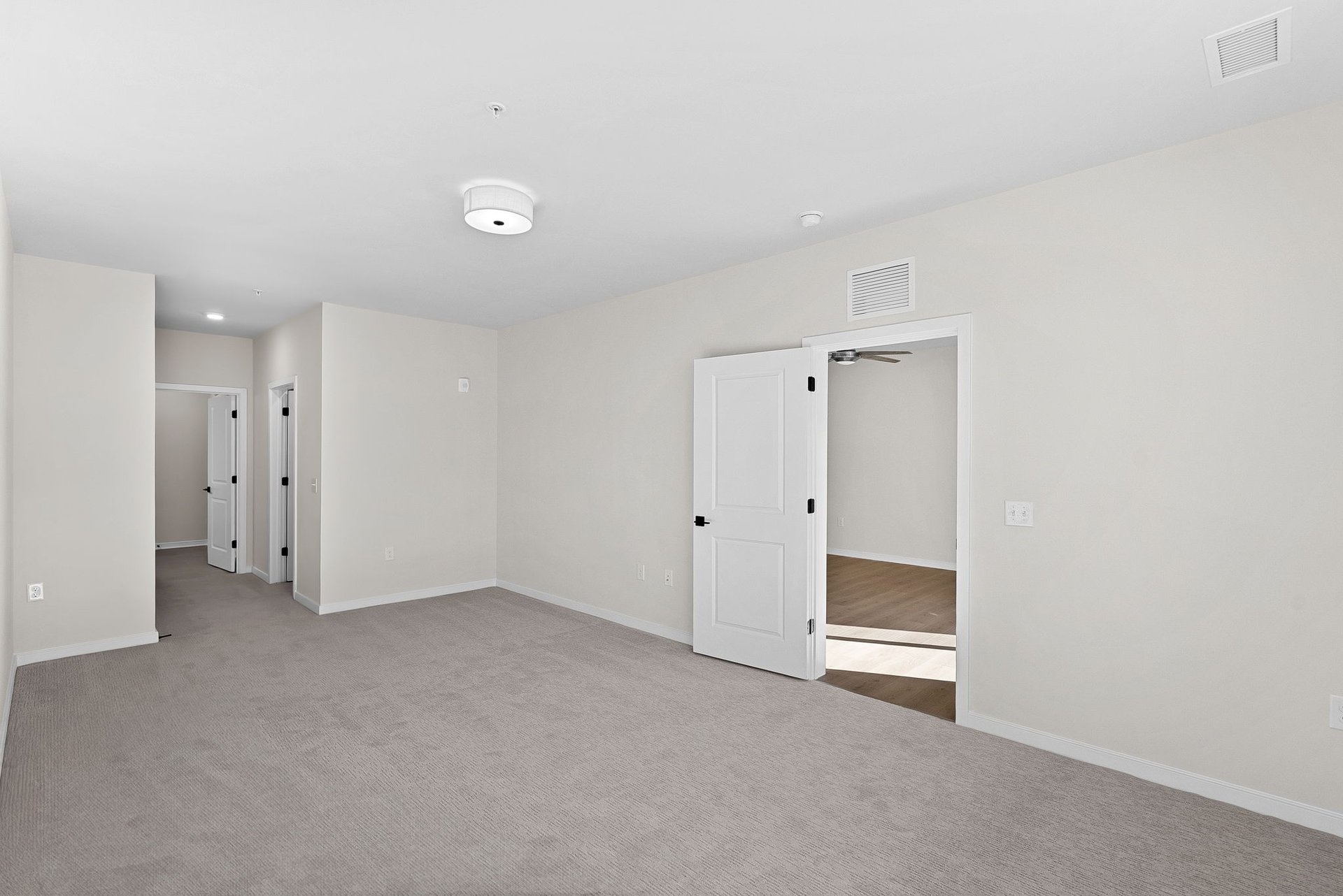 open primary bedroom with carpet and hallway to bathroom
