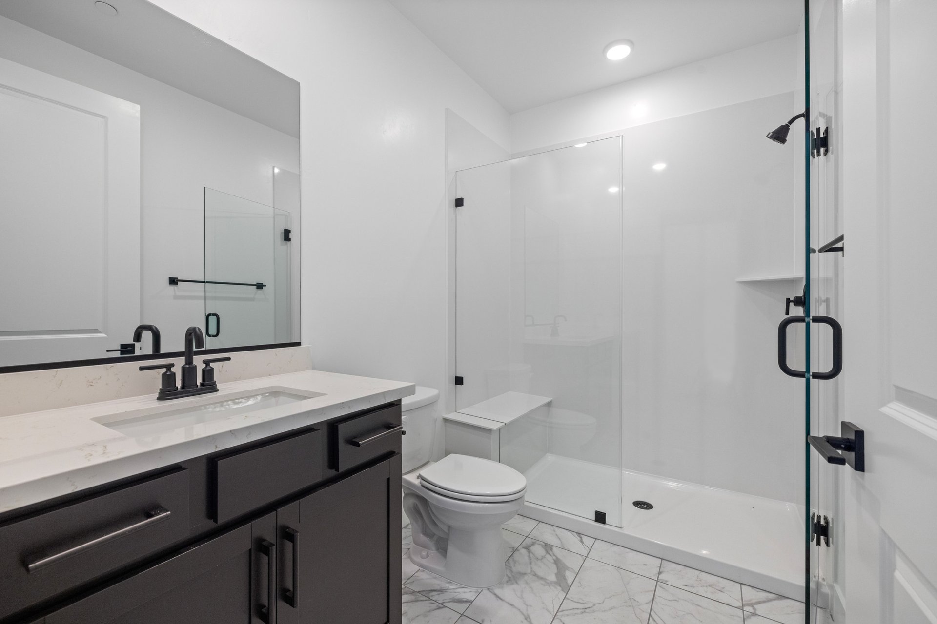 bathroom with black cabinets, white counters, and large walk-in shower with glass enclosure