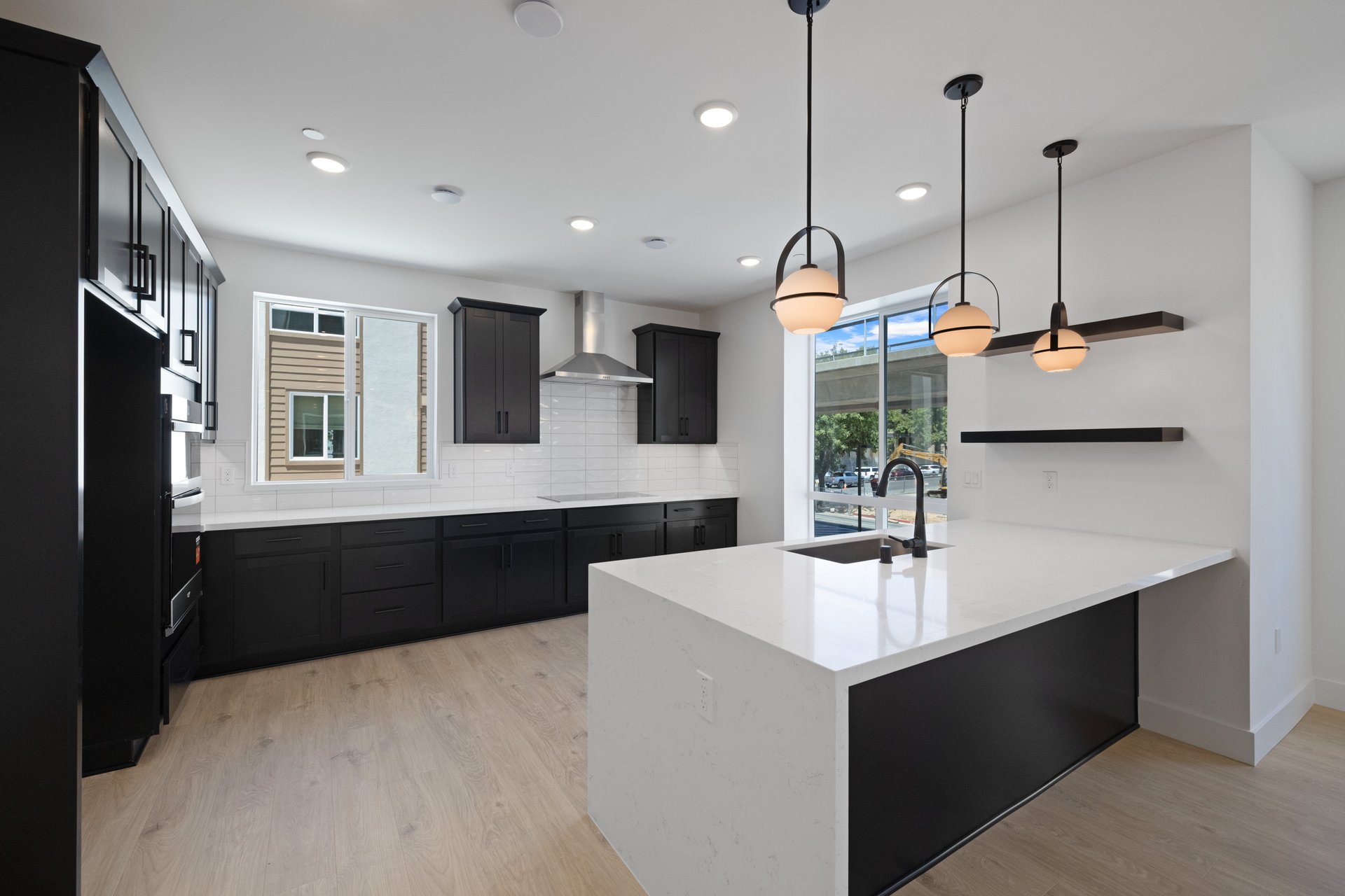 kitchen with black cabinets, white counters, light wood floors, and two windows
