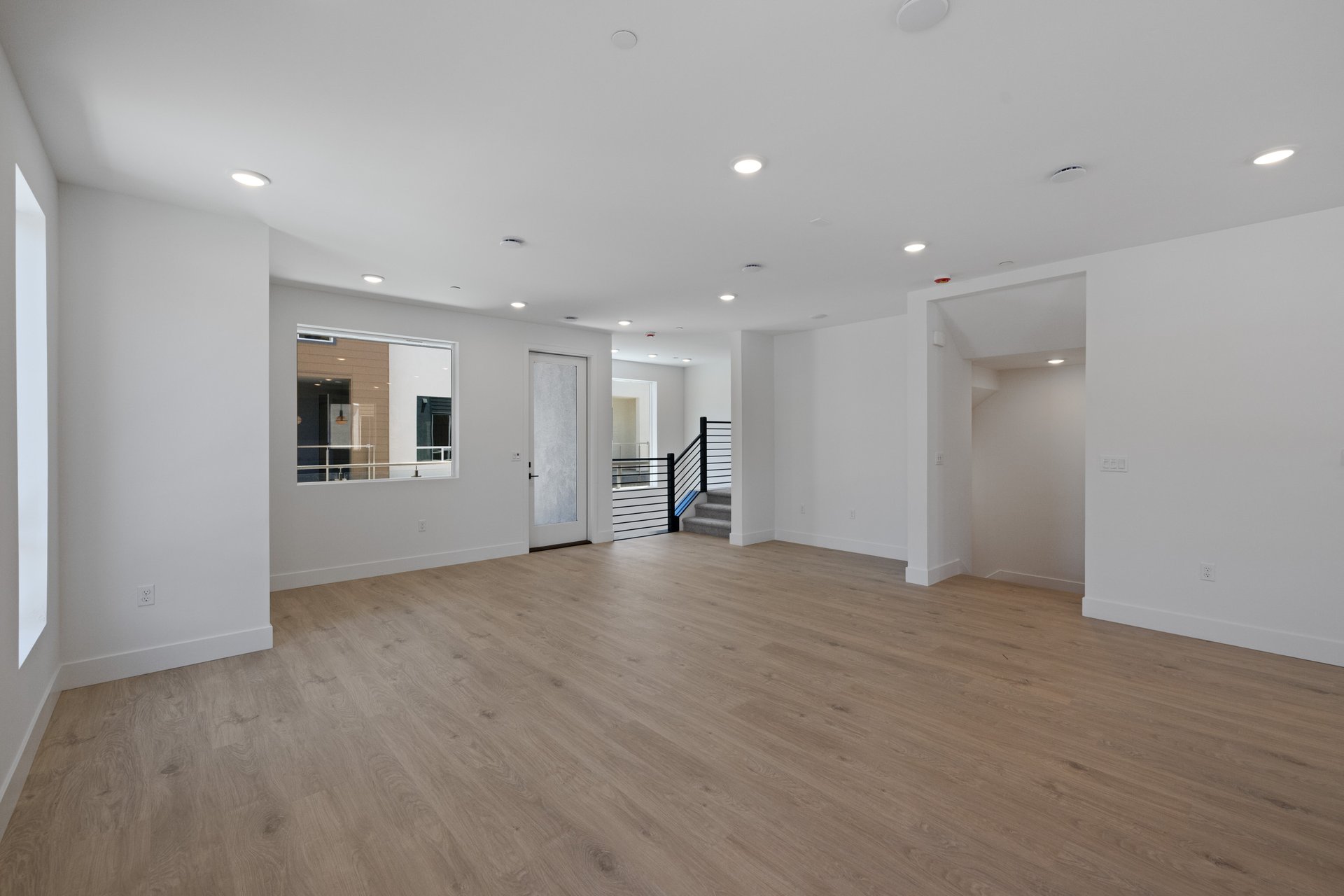 great room with light wood floors, white walls, and multiple windows