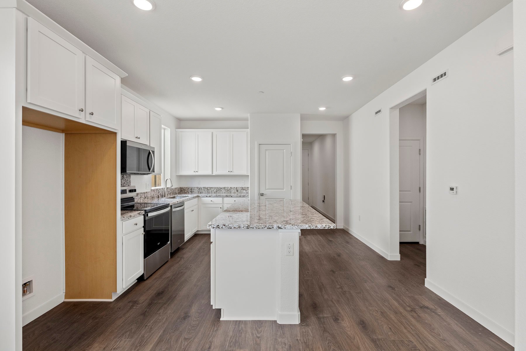 kitchen with granite counters, white cabinets, wood floors, and island