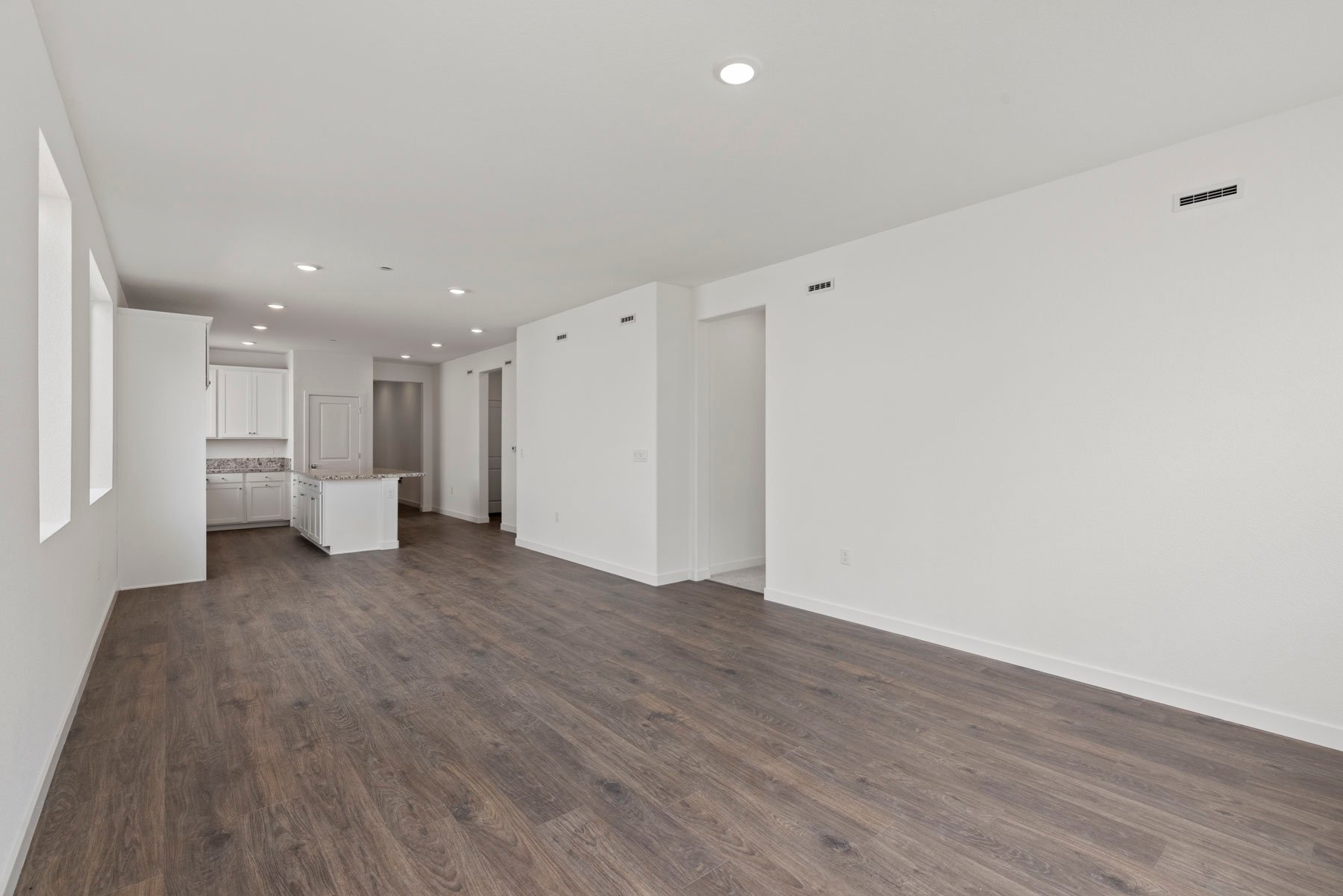 great room with wood floors, white walls, and view of adjacent kitchen