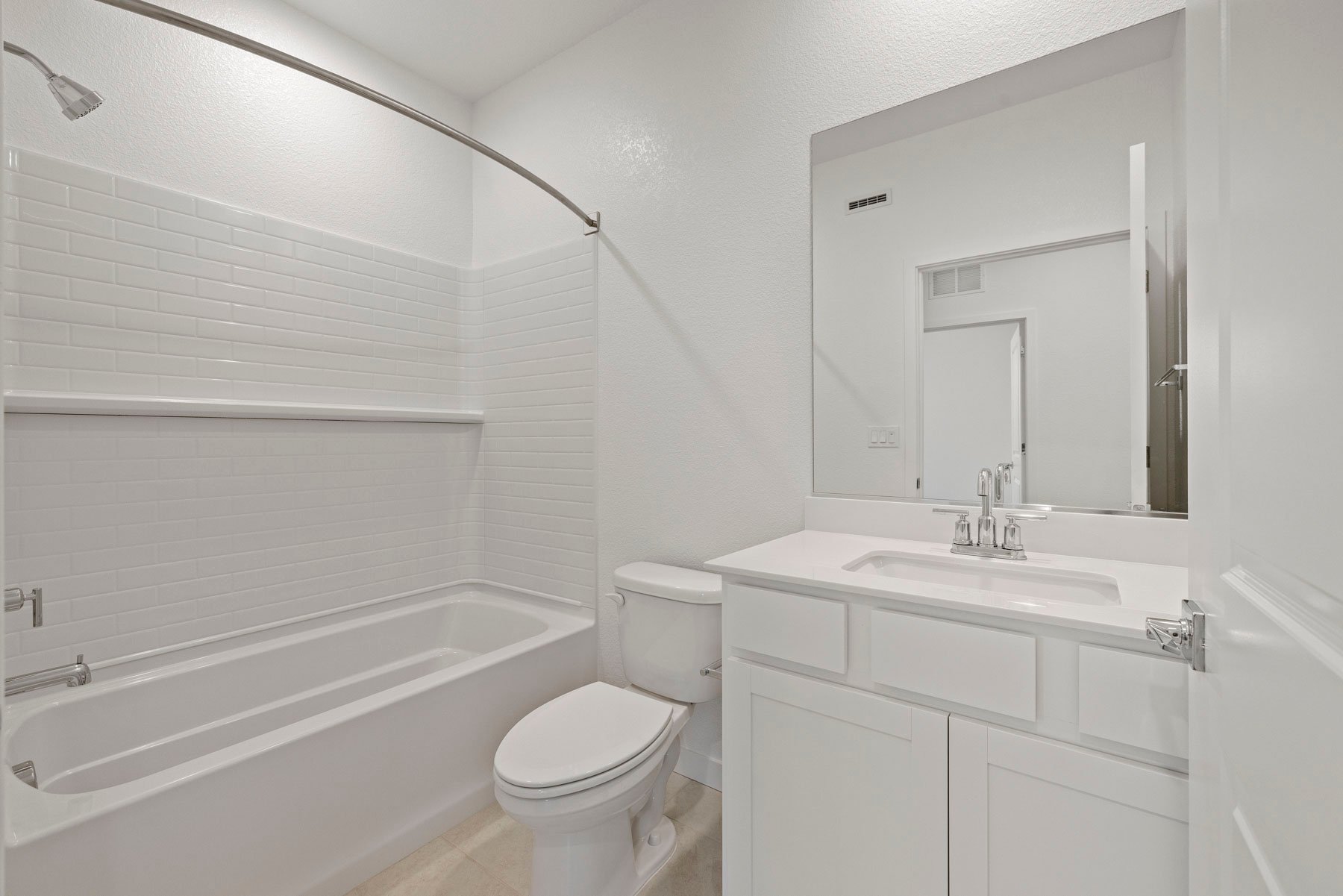 bathroom with white cabinets & counters, tan tile floor, and tub with shower overhead