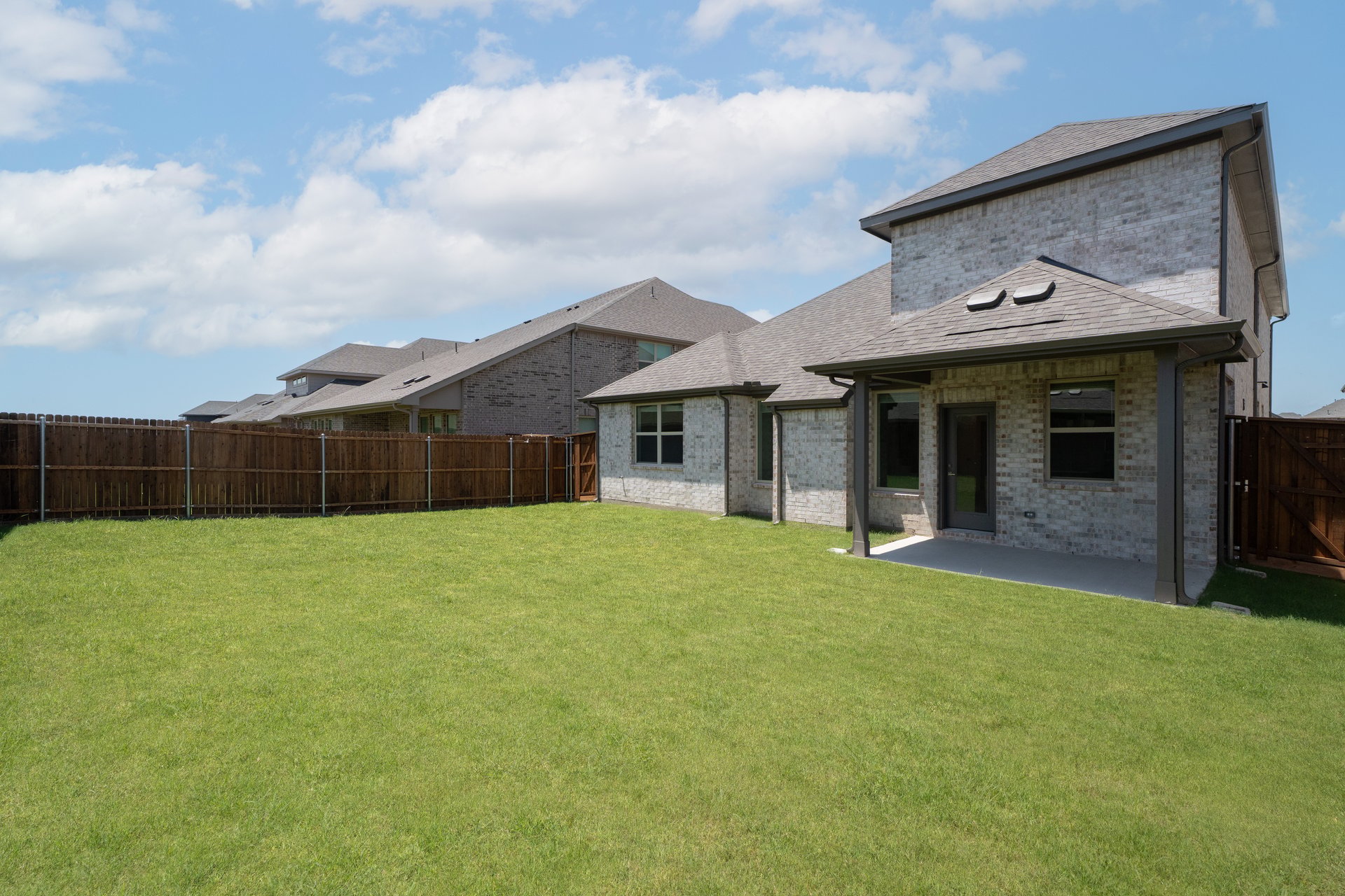 covered patio that opens up to large fenced backyard 