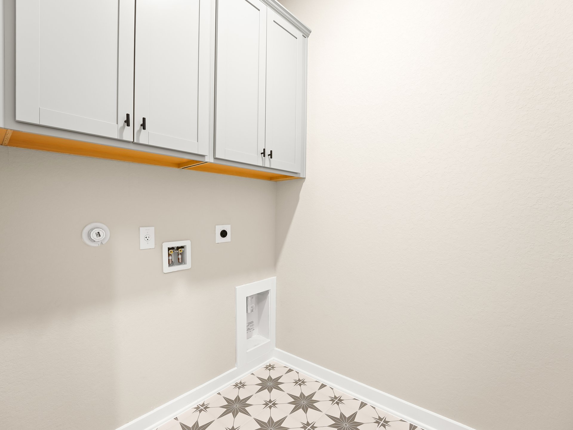 laundry room with grey and white flooring and white cabinets