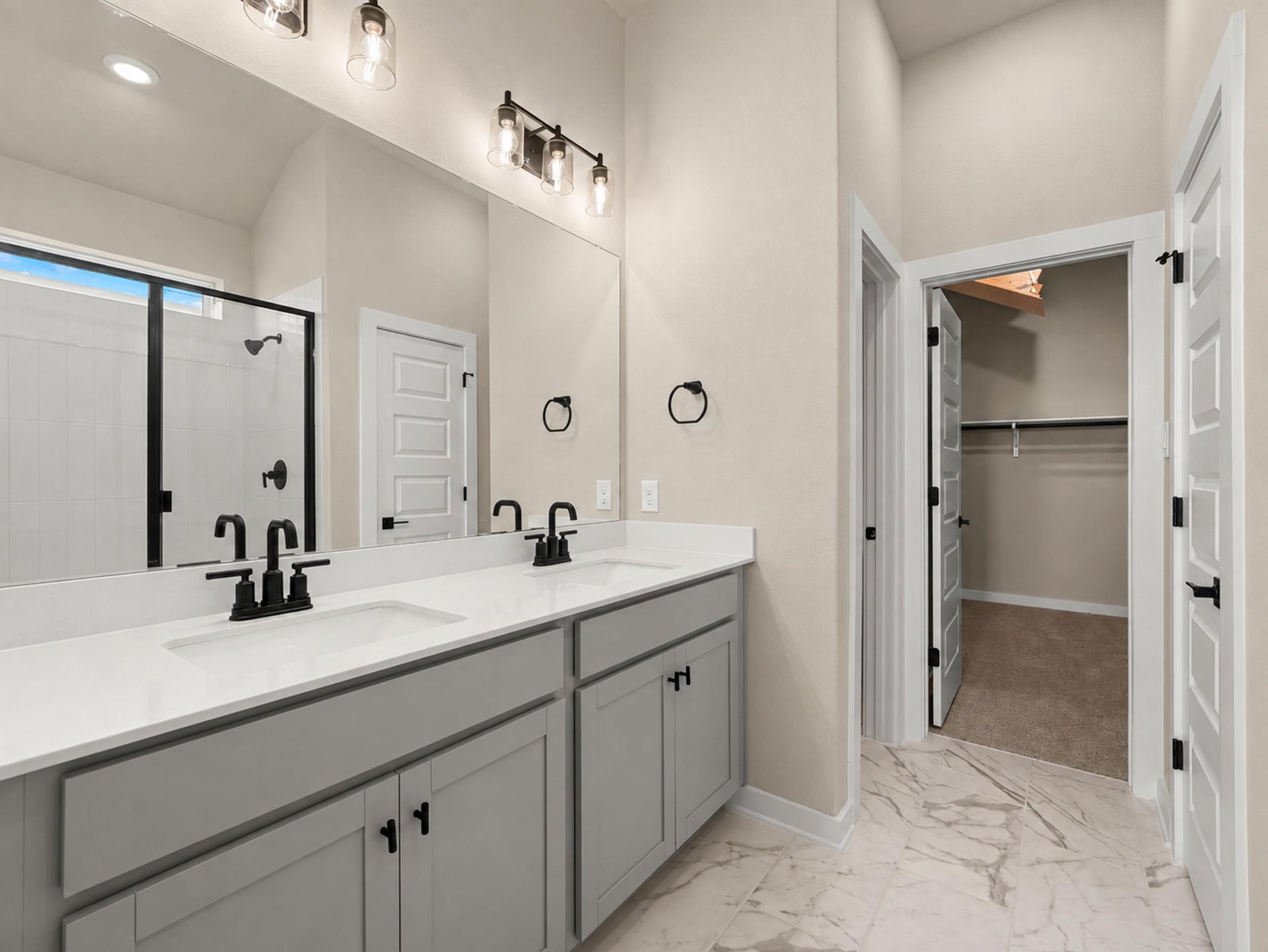 primary bath with dual sinks, grey cabinets and white flooring