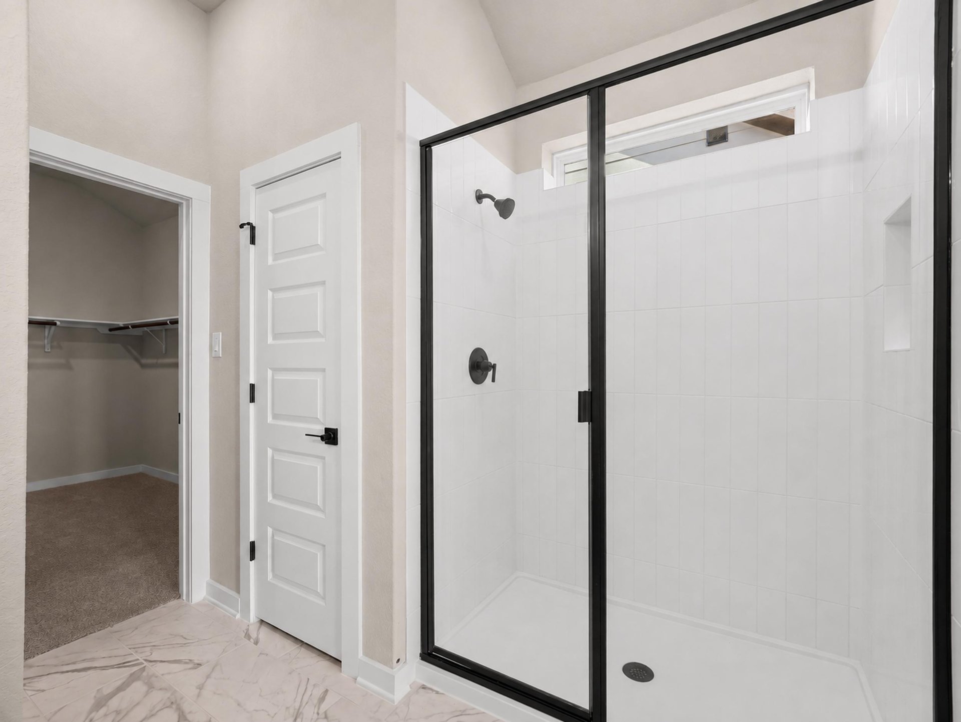 primary bathroom with shower and white flooring
