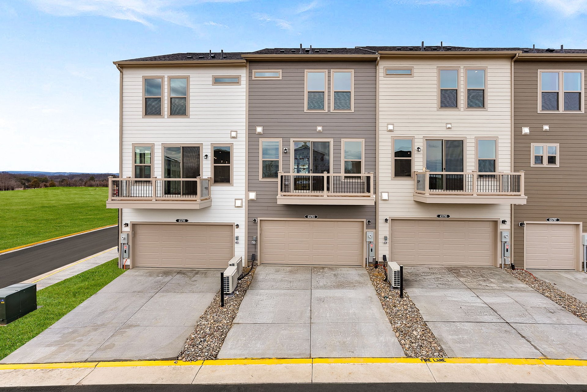 three-story townhome rear exterior with a 2-car garage and a deck