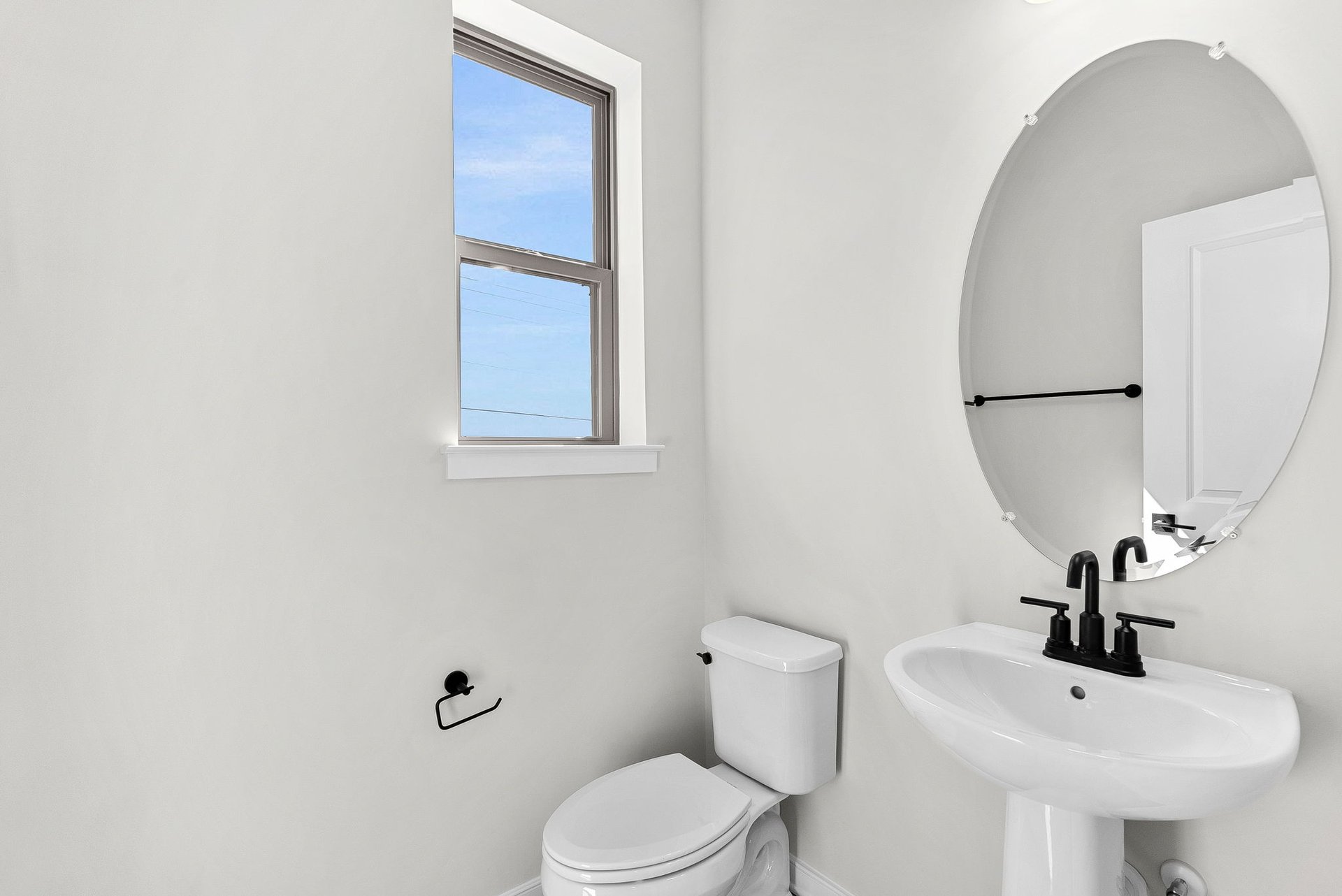 powder room with an oval mirror and a window