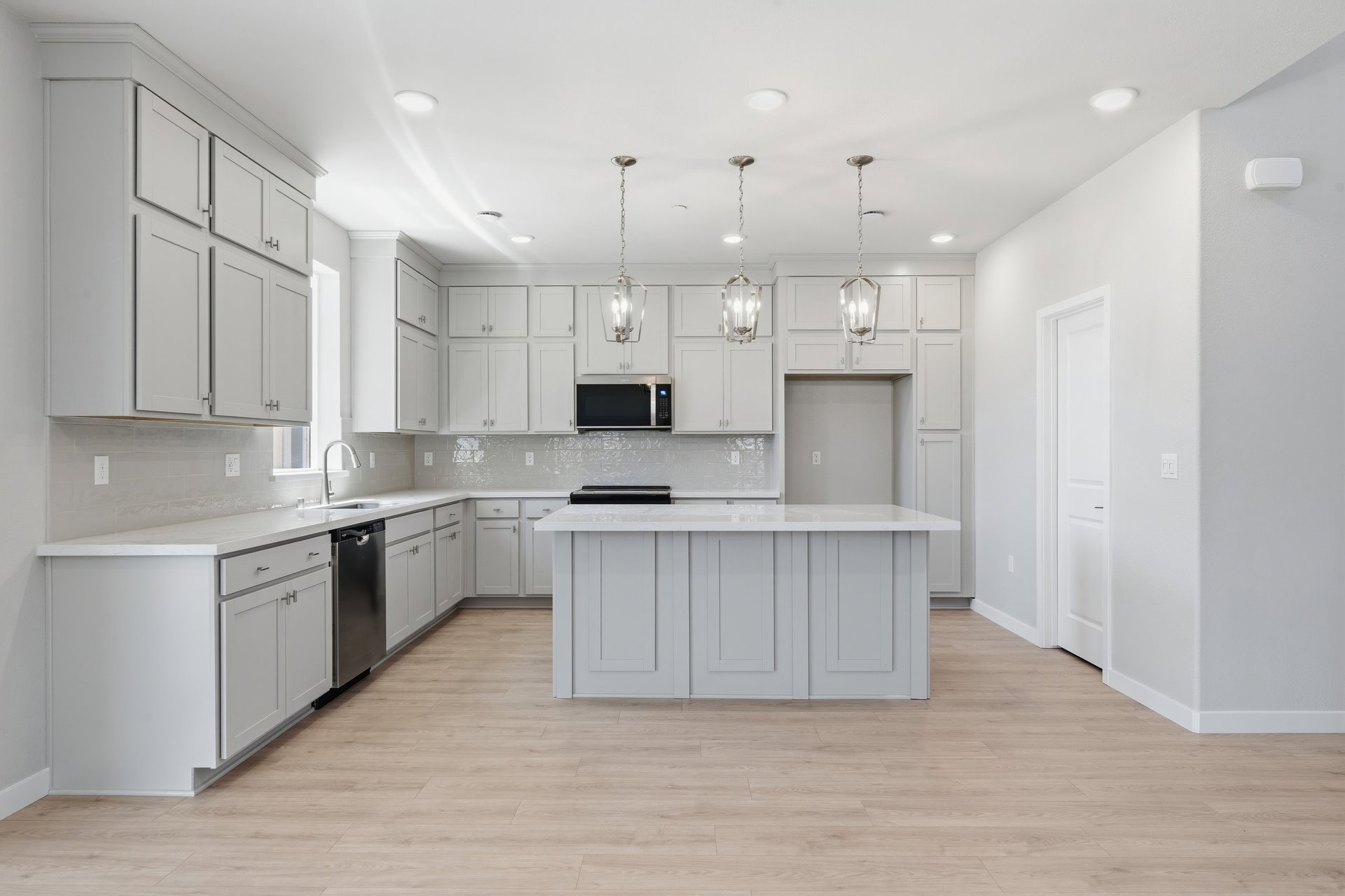 kitchen with light wood floors, light gray ceiling height cabinets, white quartz counters, and window above sink