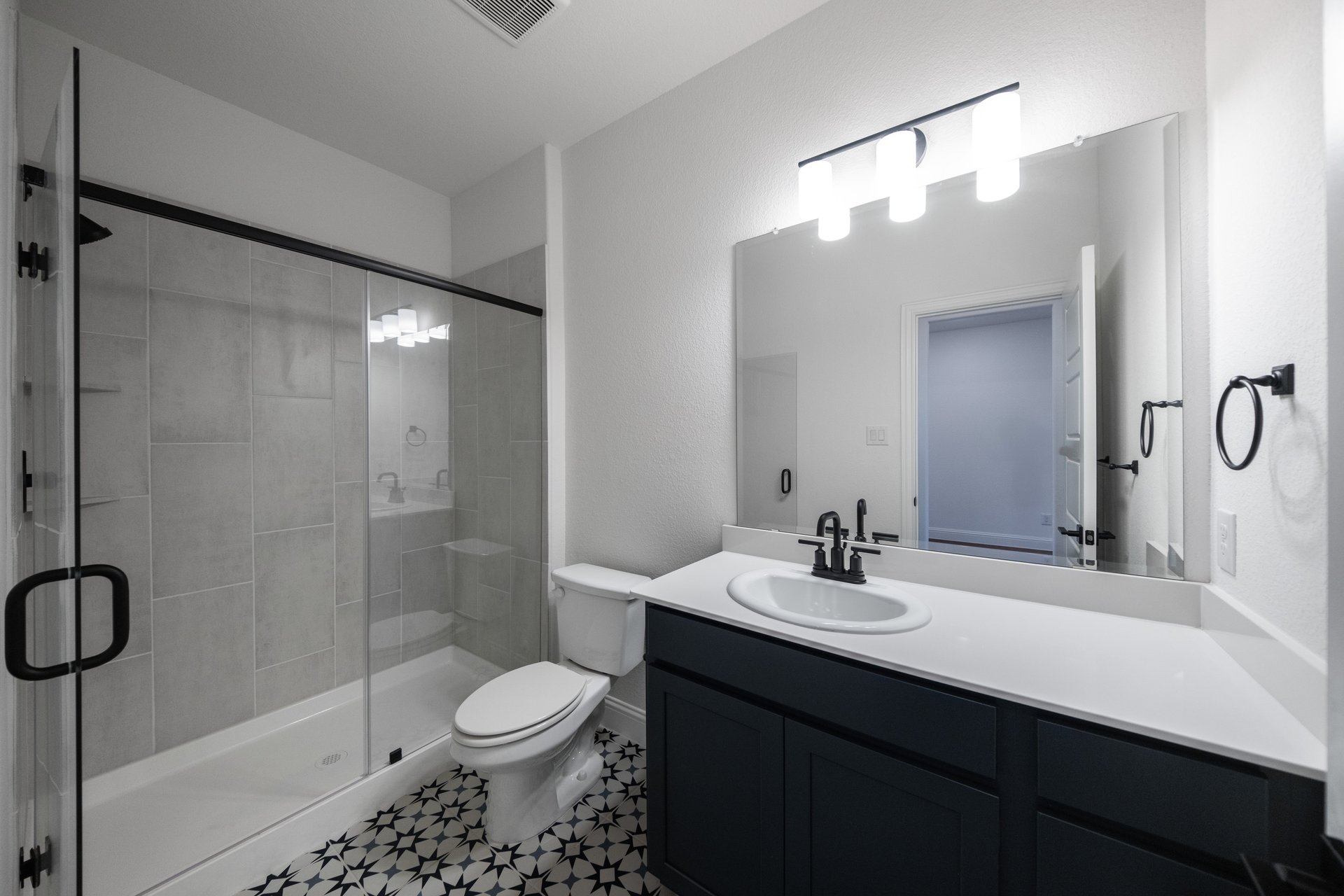 bathroom with walk-in shower and dark cabinets 