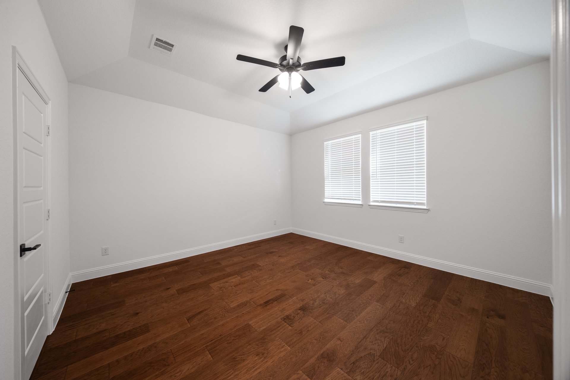 bedroom with wood flooring and windows with blinds 