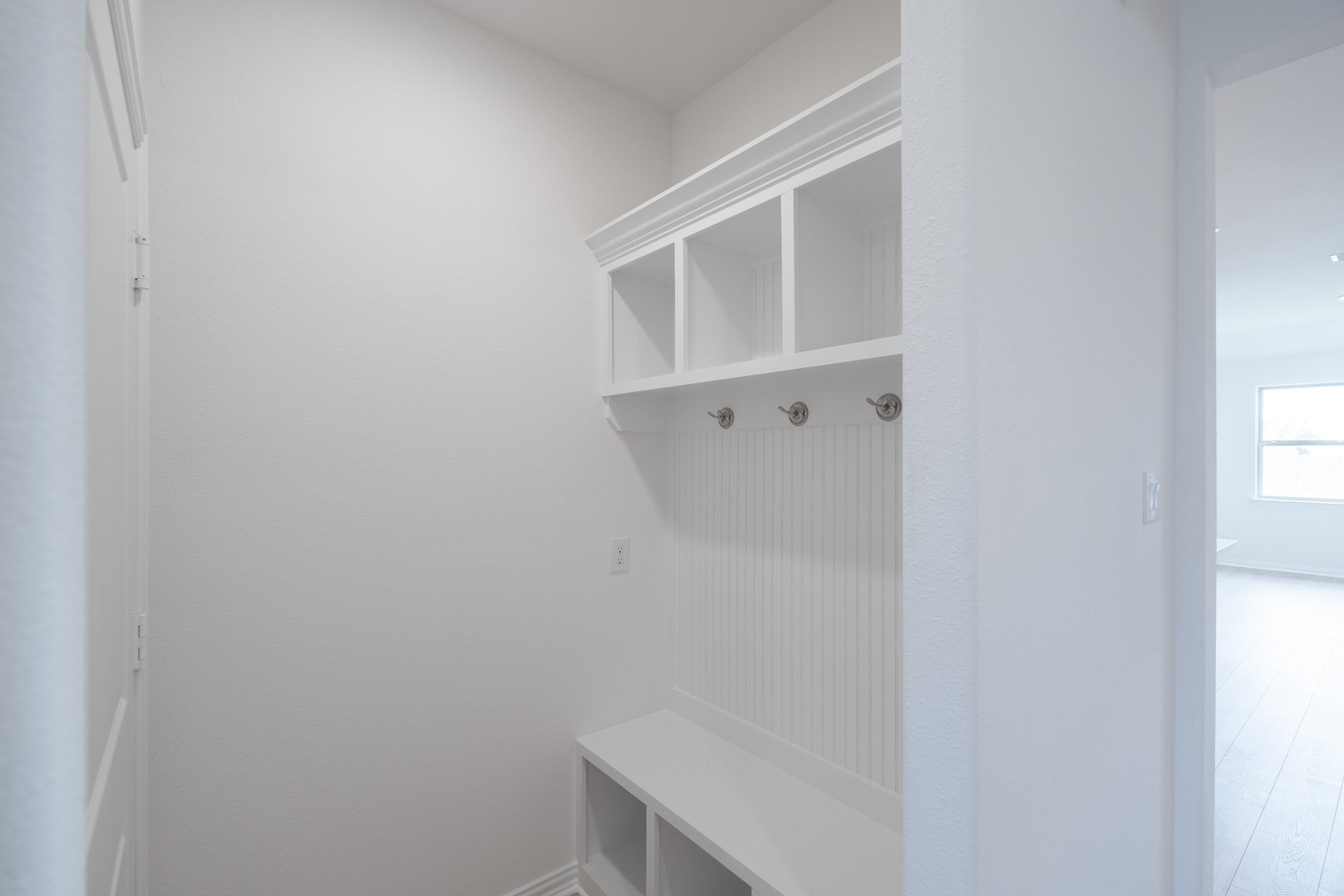 mudroom with wood floors and white shelves with bench