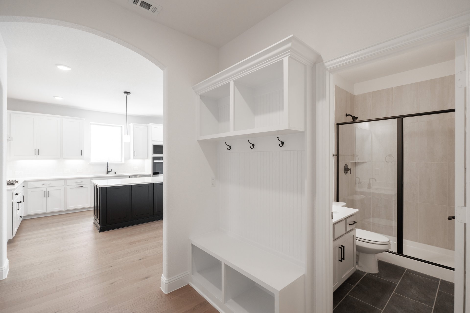 mudroom with wood floors and white shelves with bench