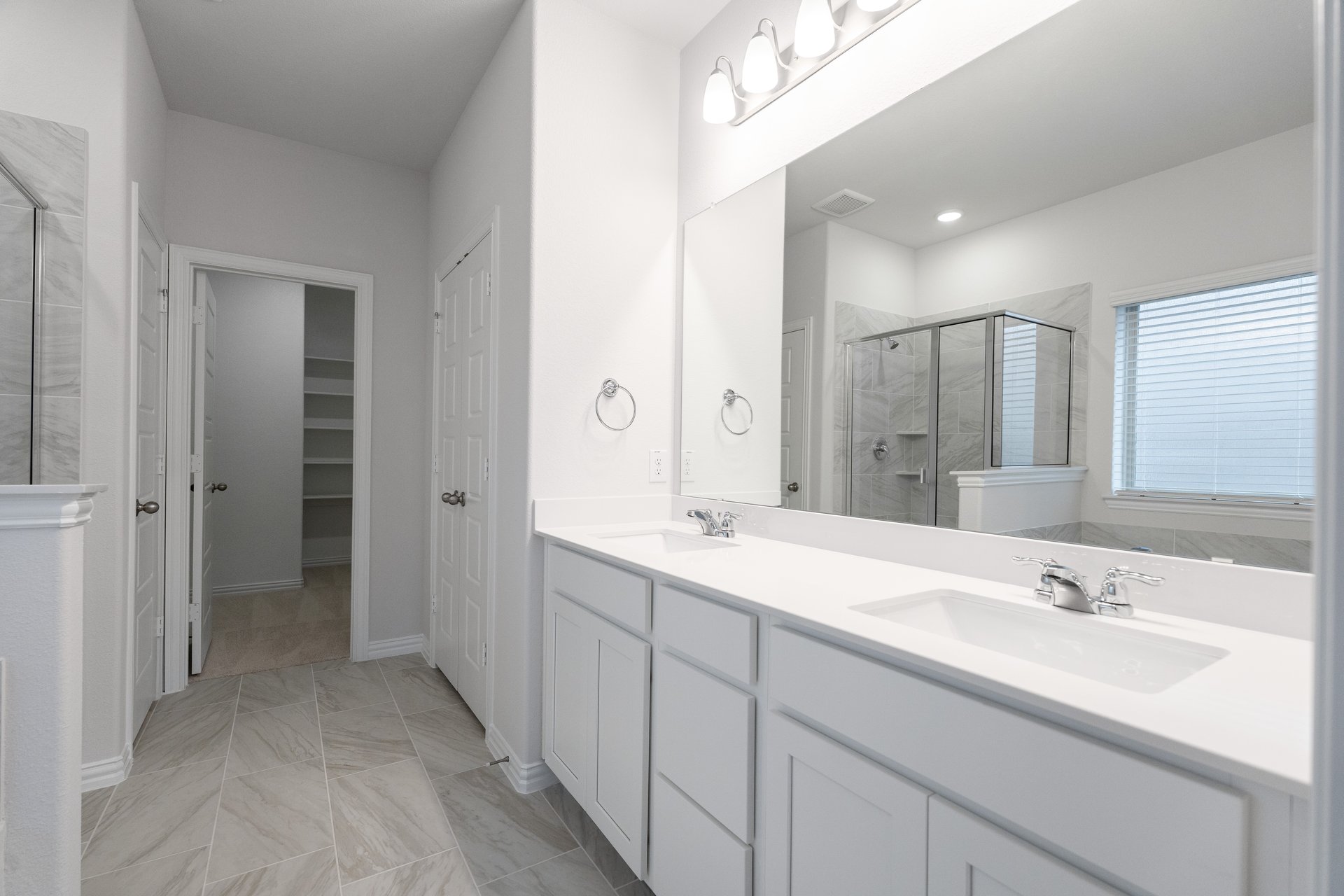 primary bathroom with white cabinets and tile floors 