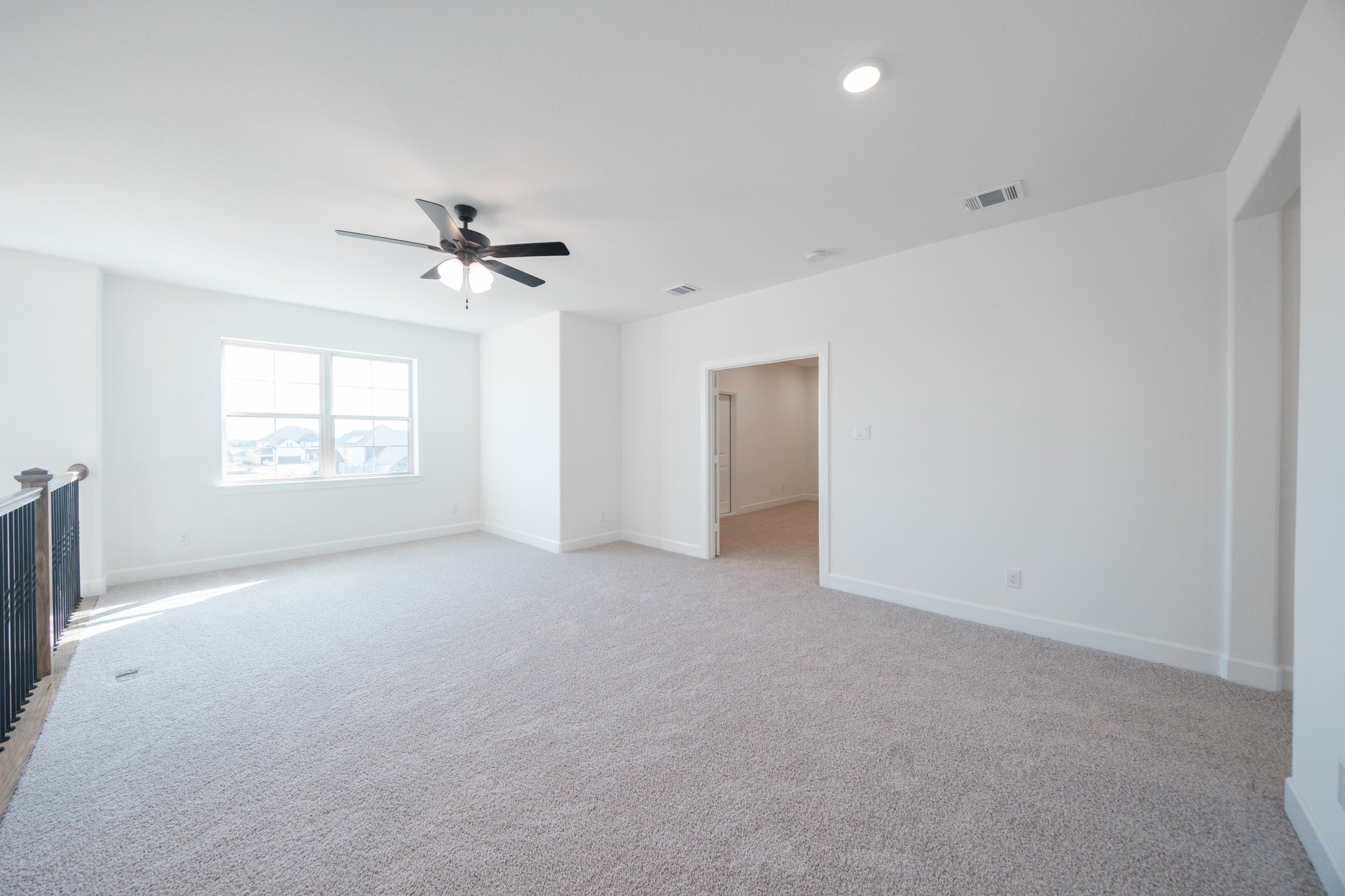 open loft with carpet and ceiling fan