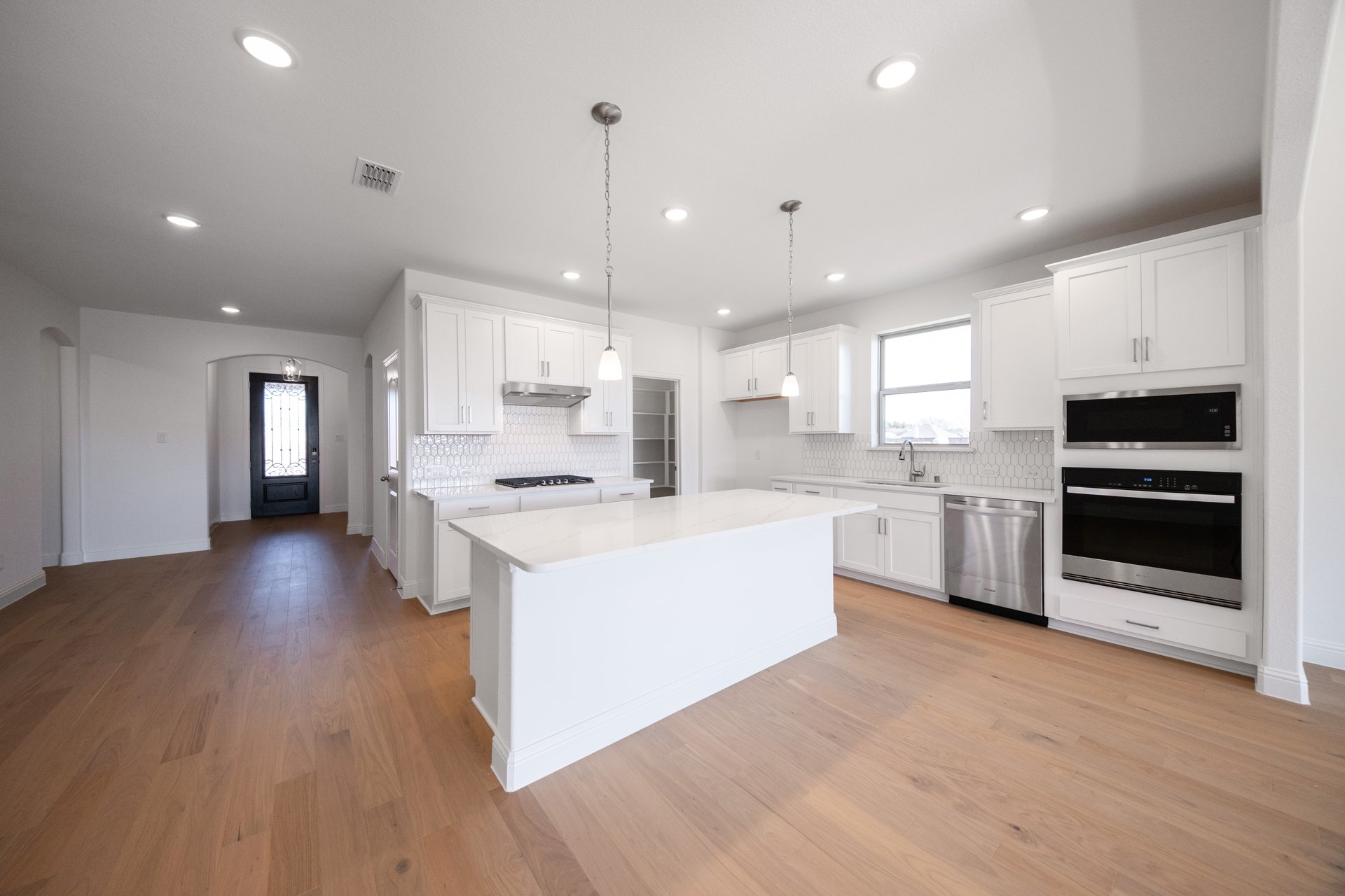 open kitchen with wood floors and white cabinets