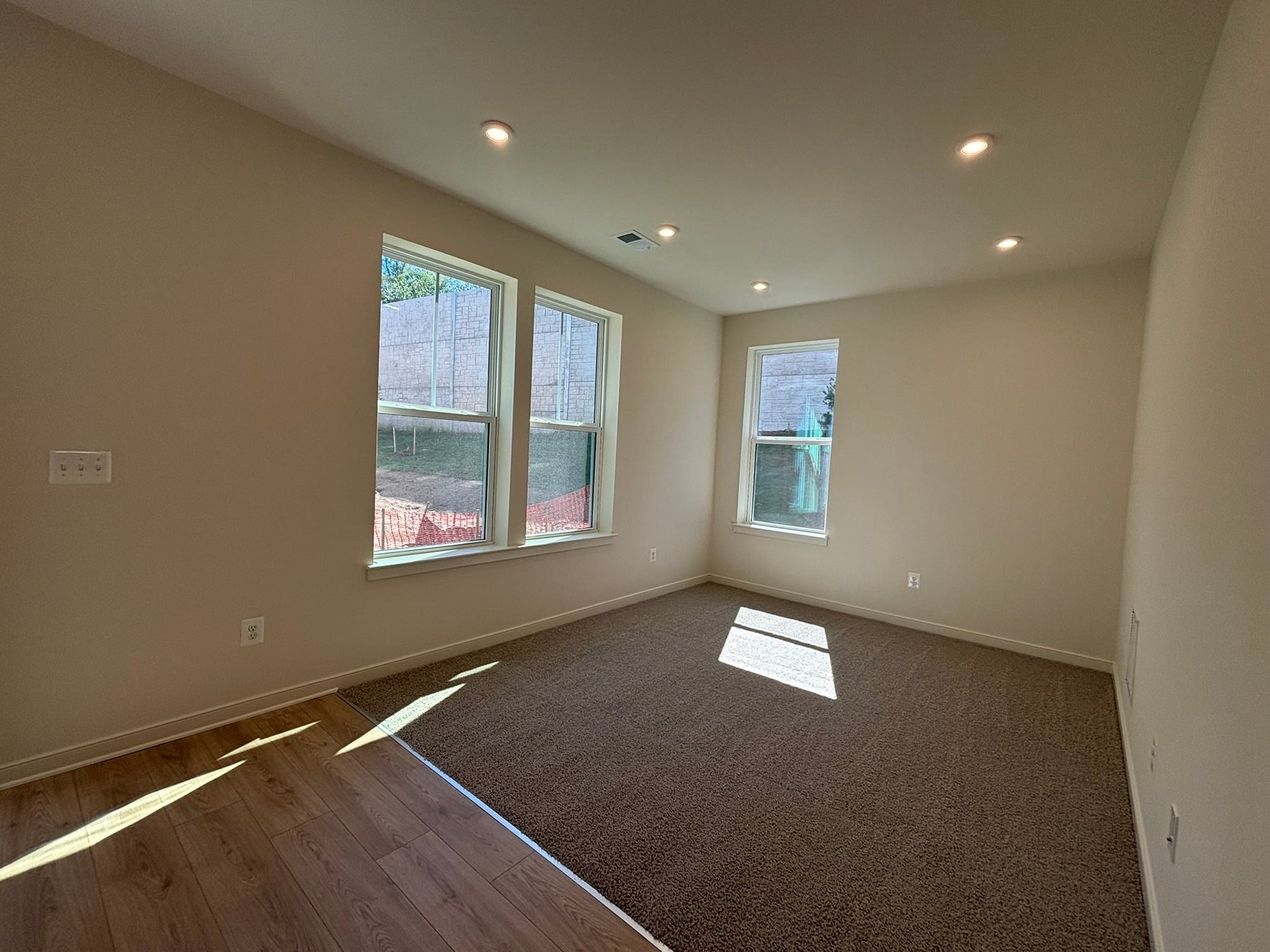 recreation room with three windows and carpet