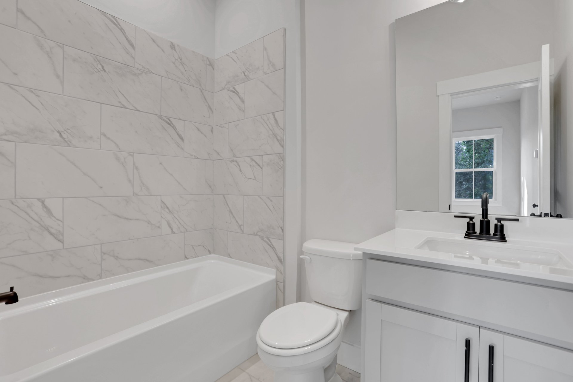 bathroom with white cabinets and tile shower