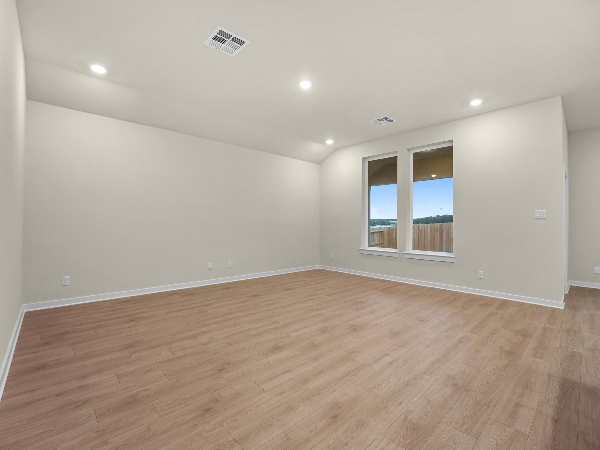 great room with brown flooring, two windows and sloped ceiling