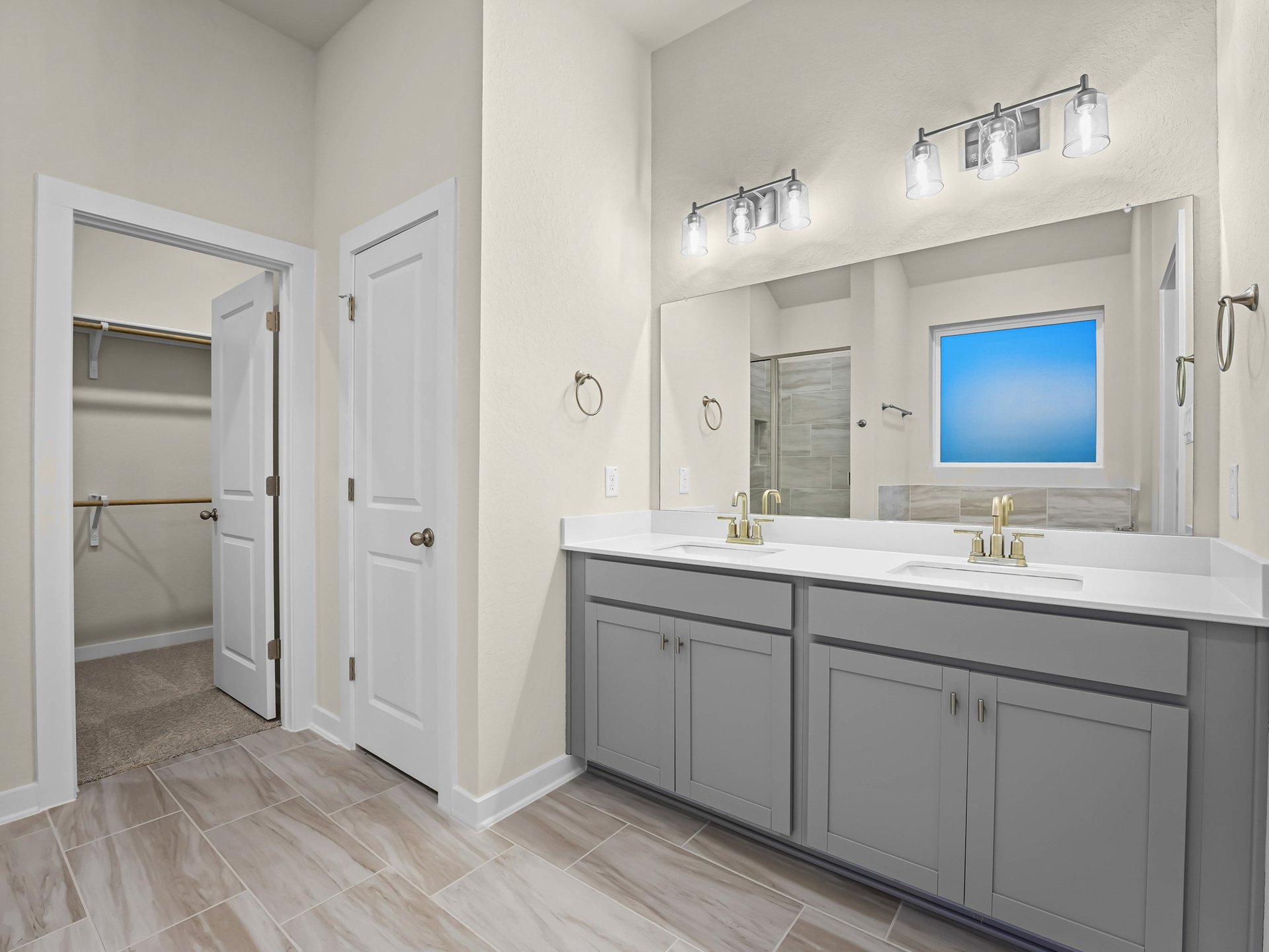 primary bathroom with dual sinks, gray cabinets and brown flooring