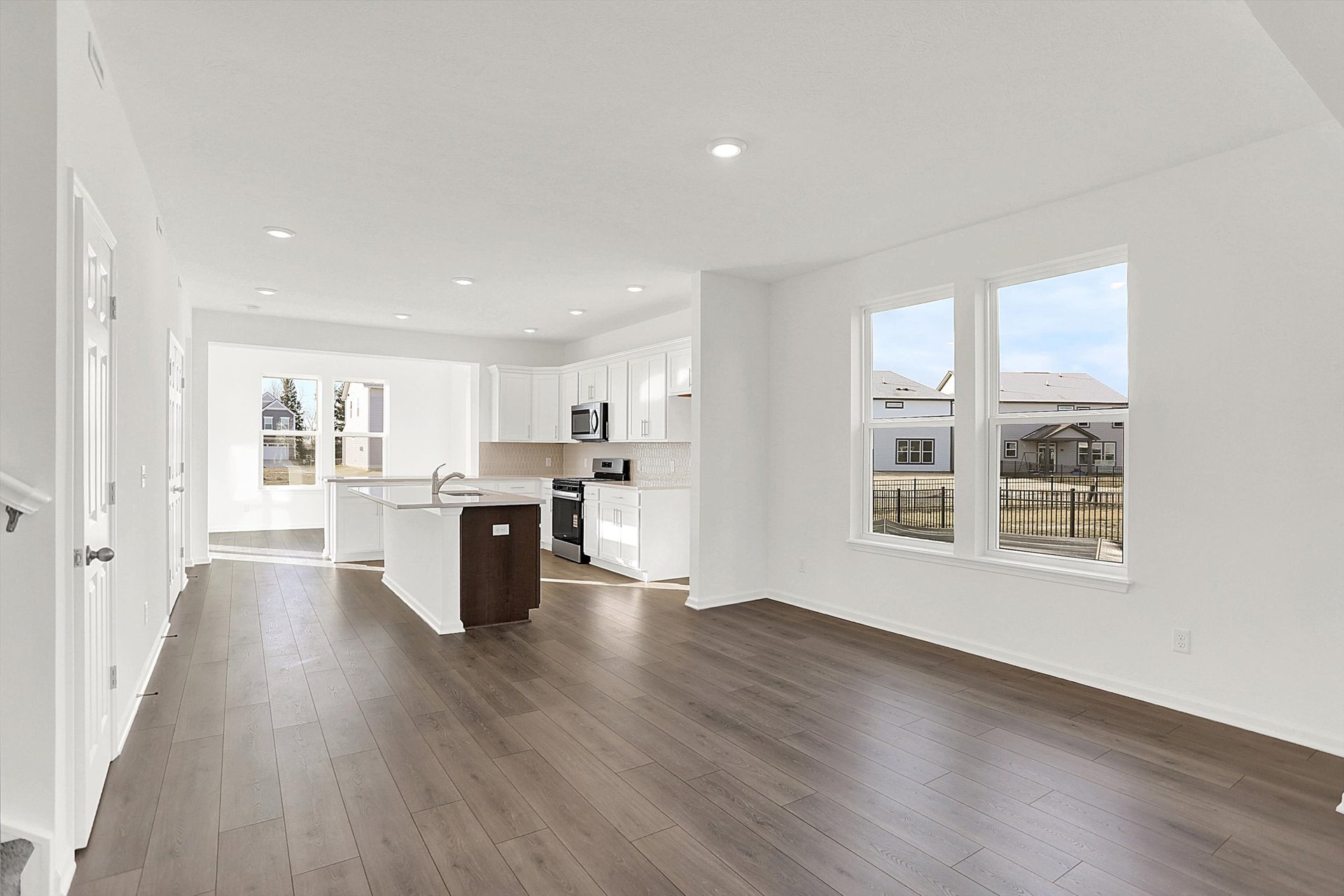 dining area with dark wood plank flooring open to the kitchen