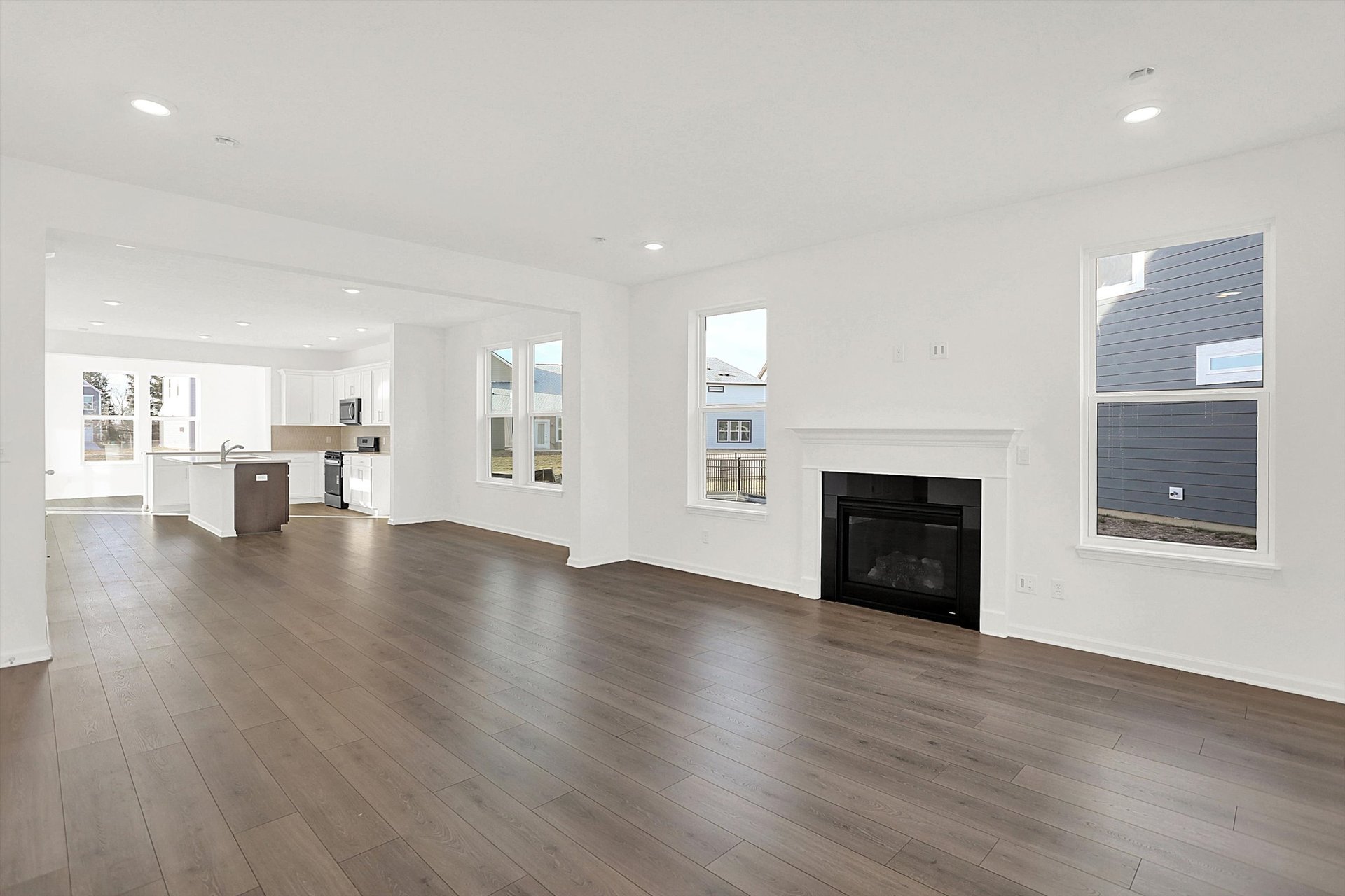 open-concept great room with fireplace and plank flooring