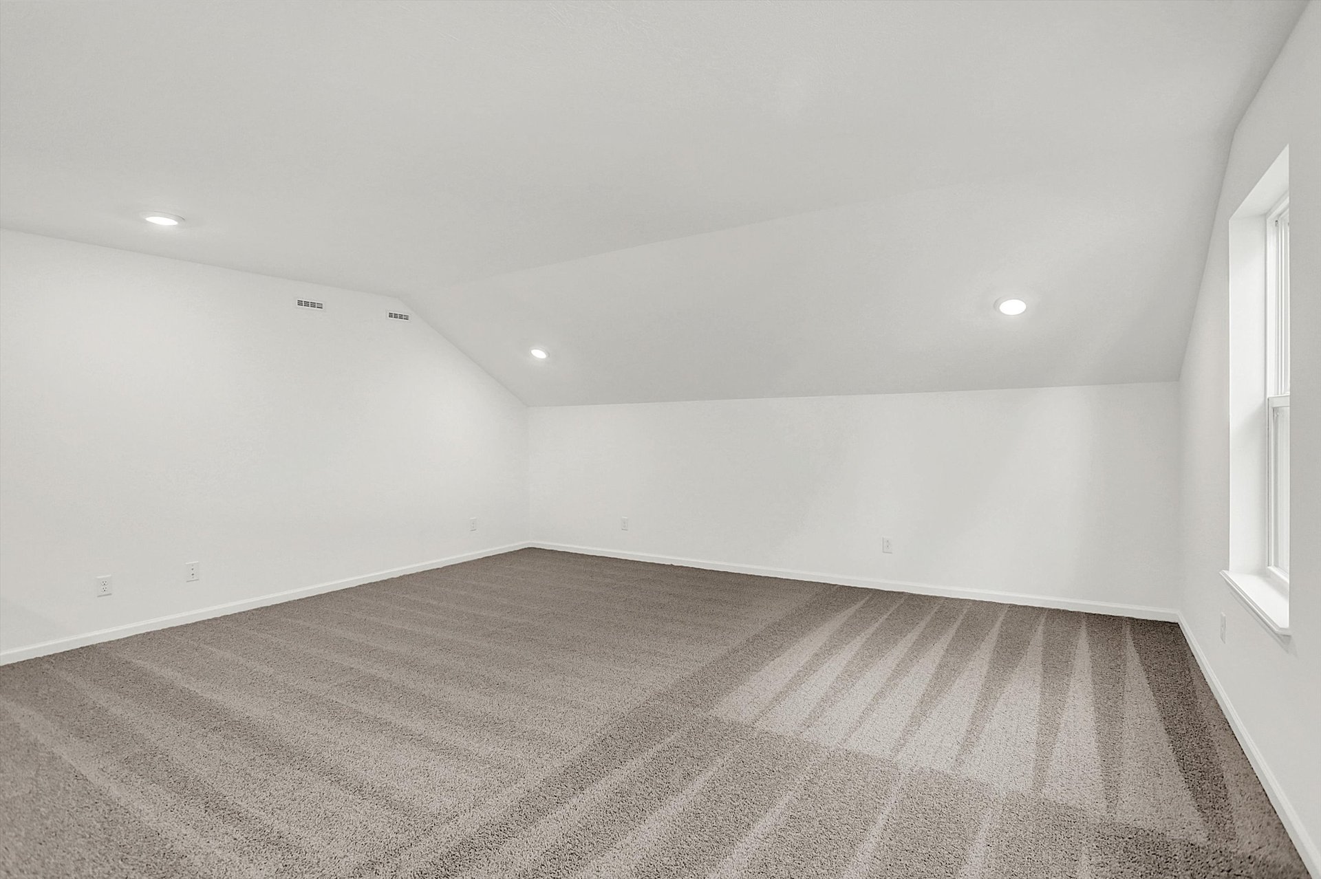large loft with gray carpet and sloped ceilings