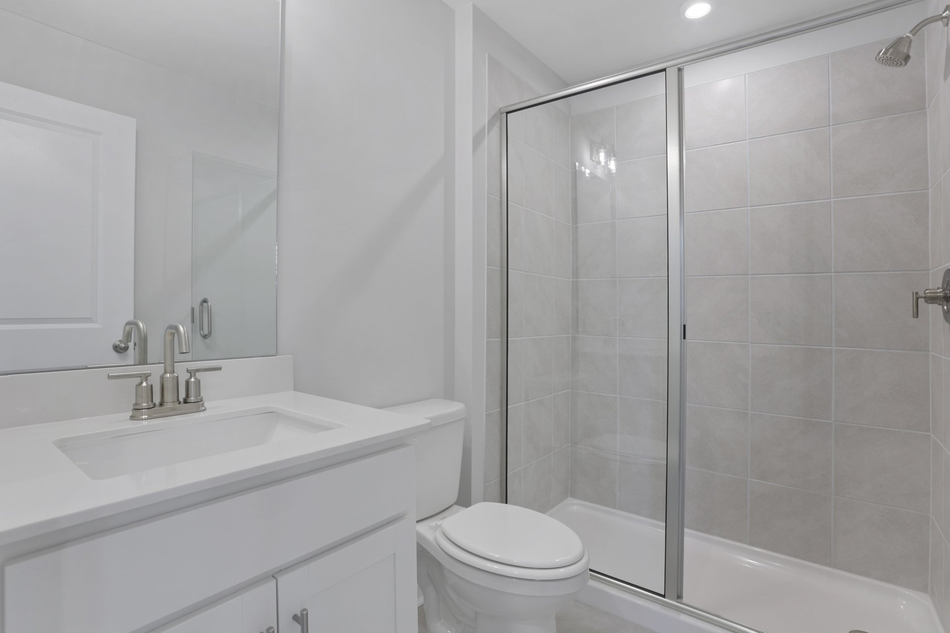 bathroom with gray cabinets and tile shower