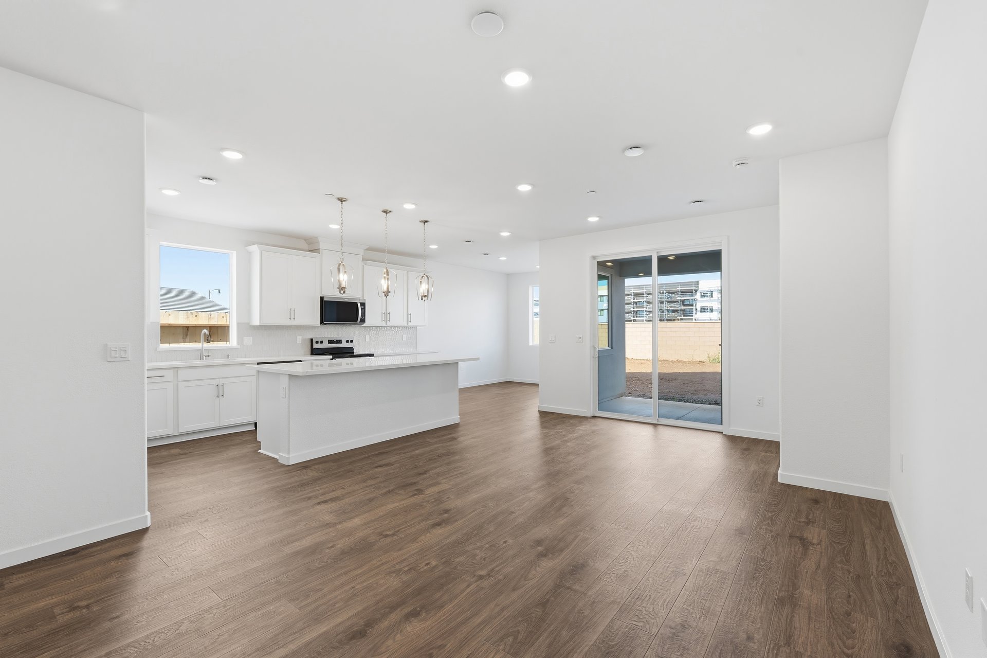 great room with wood floors, white walls, recessed ceiling lights, and sliding glass door to back patio