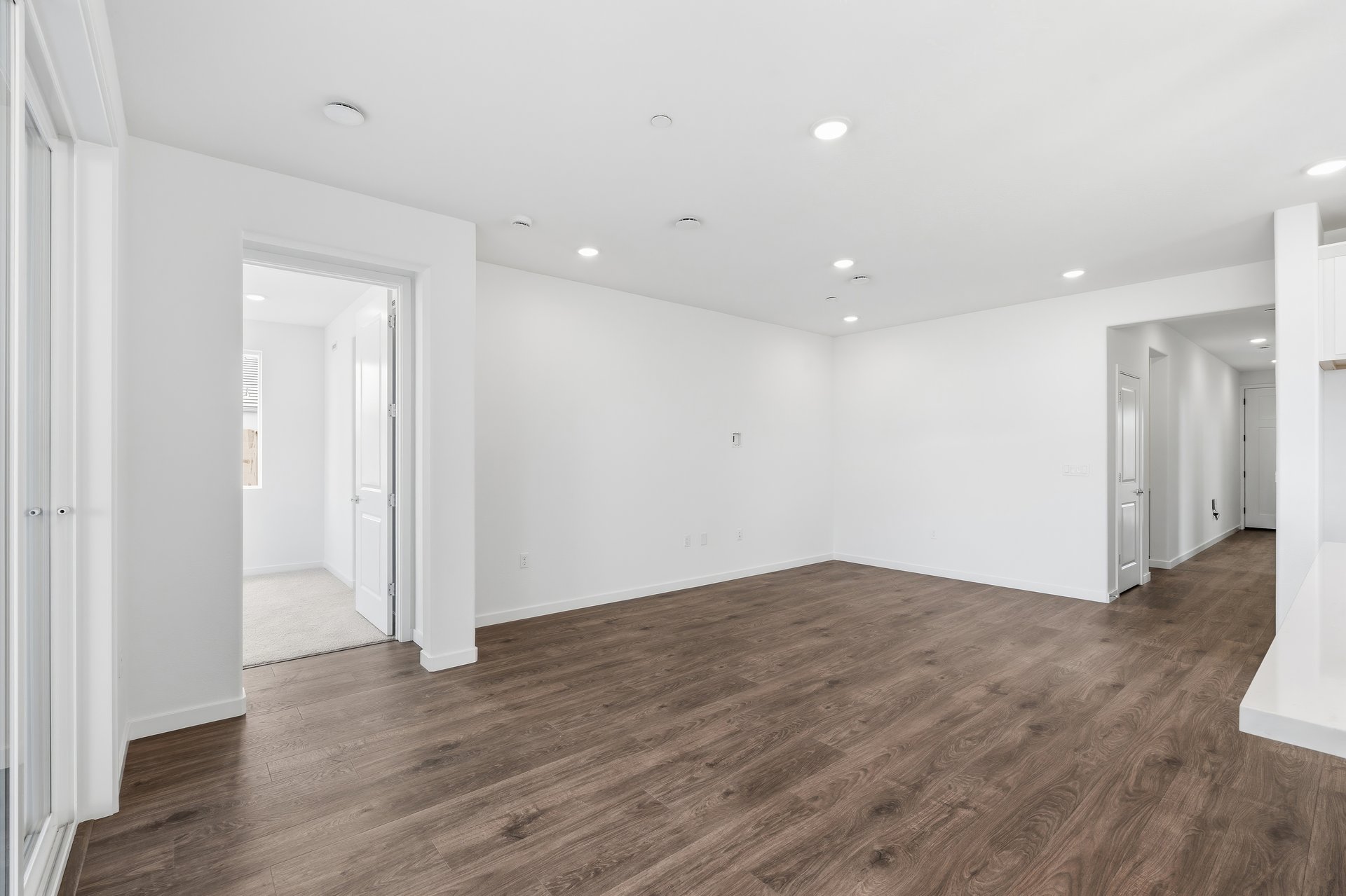 great room with wood floors, white walls, recessed ceiling lights, and view of entry foyer