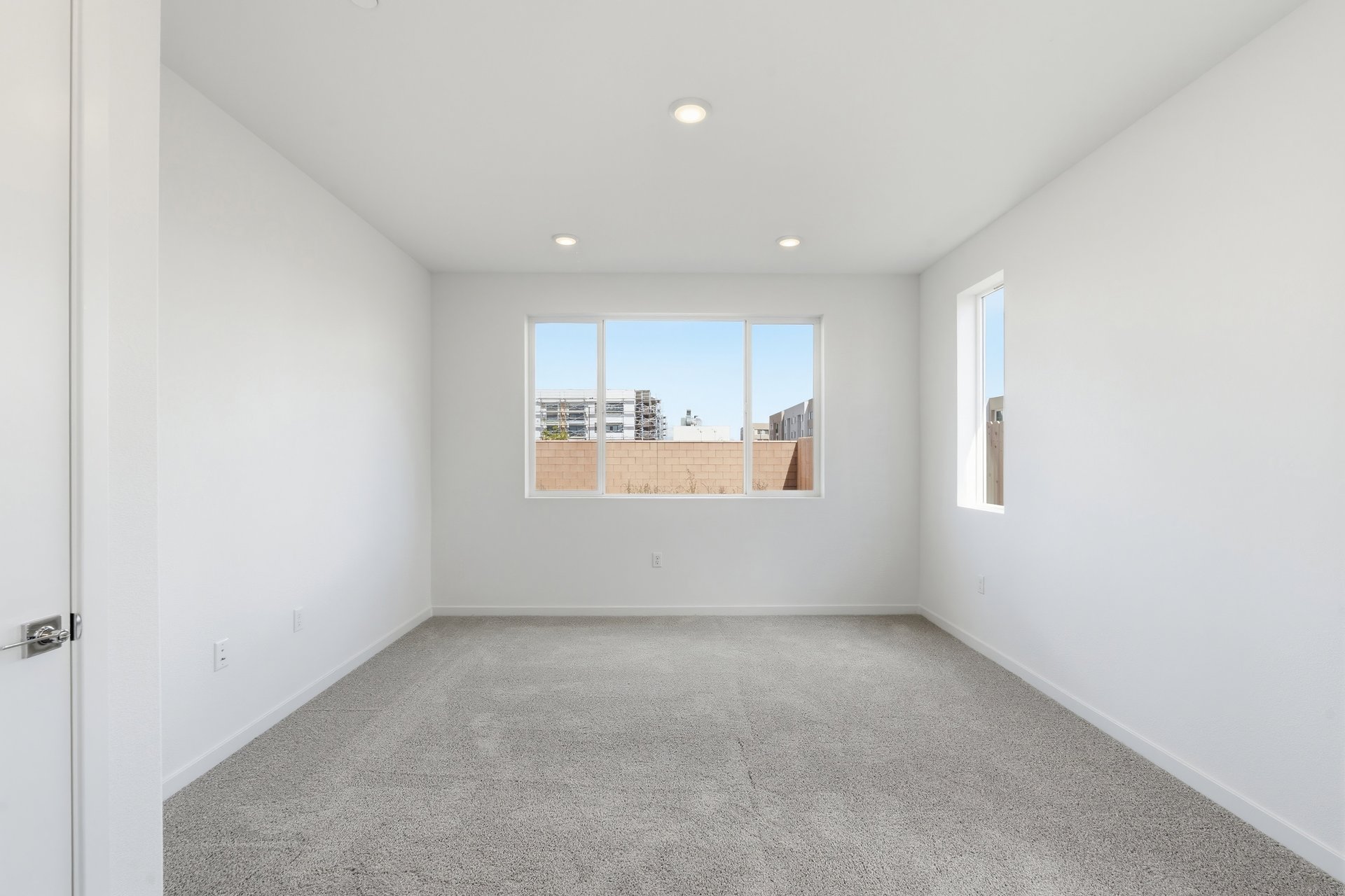 bedroom with tan carpet, white walls, recessed ceiling lights, and two windows