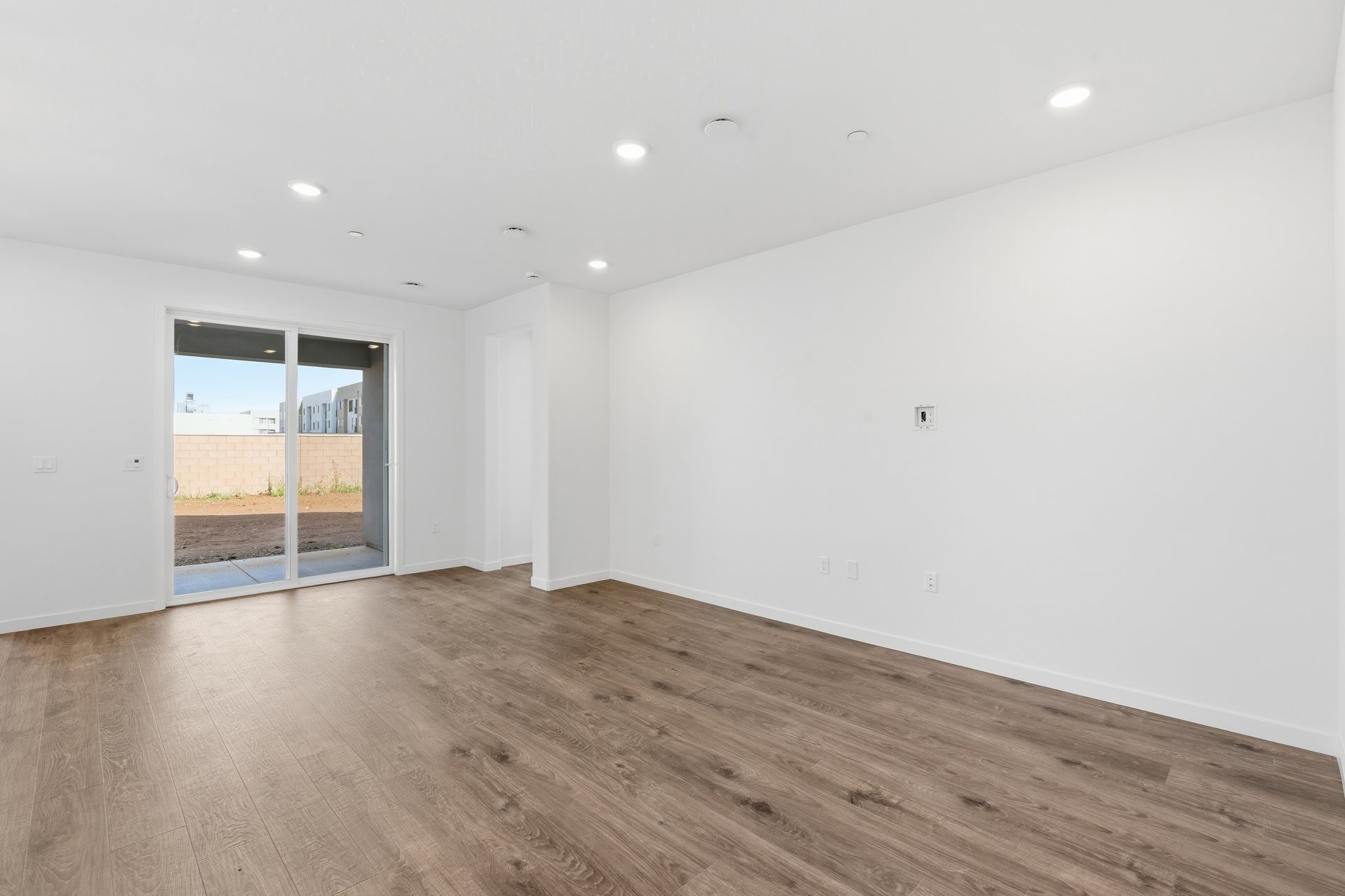 great room with wood floors, white walls, recessed ceiling lights, and sliding glass door to back covered patio