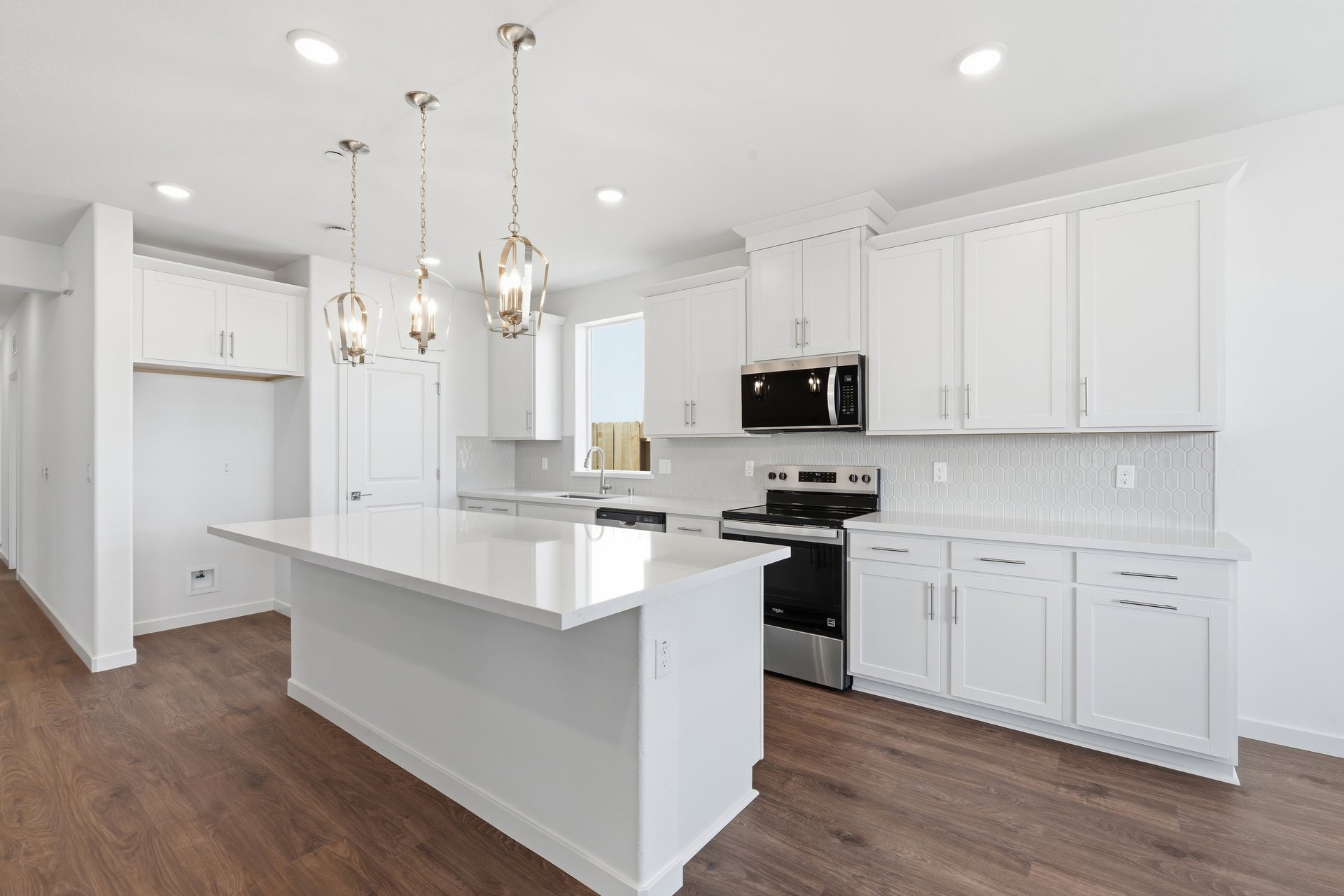 kitchen with white cabinets, white quartz counters, island, wood floors, and window above sink