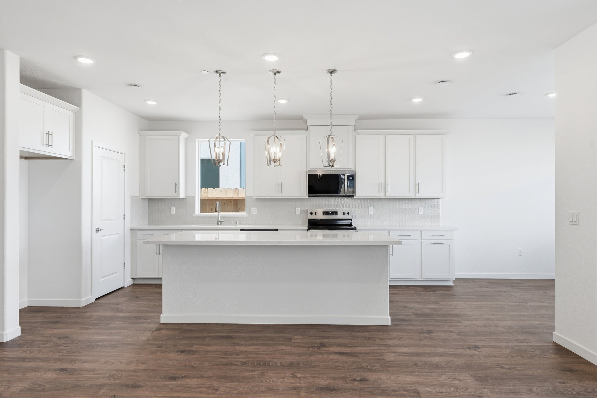 kitchen with white cabinets, white quartz counters, center island, wood floors, and window