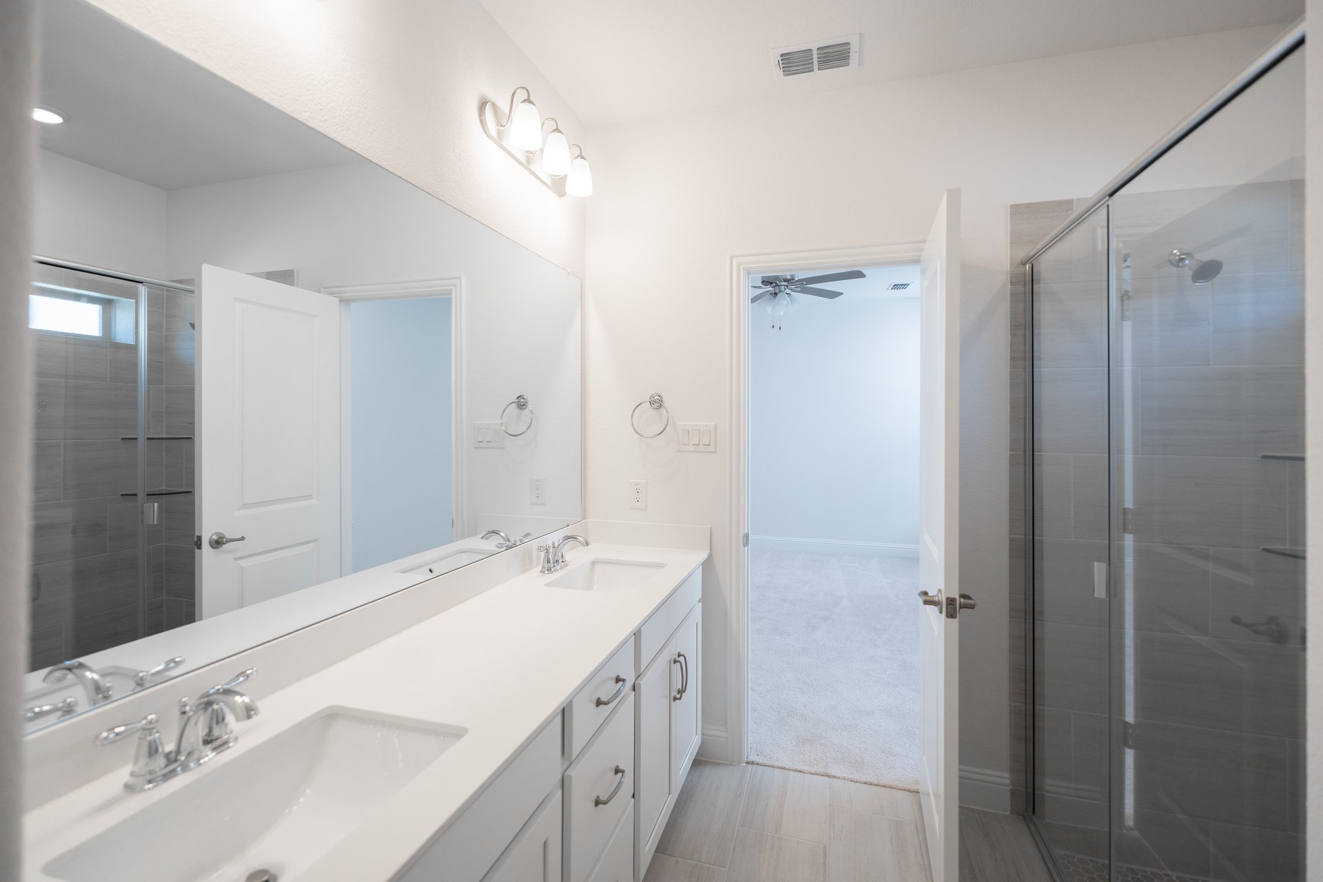 primary bathroom with walk-in shower and white cabinets