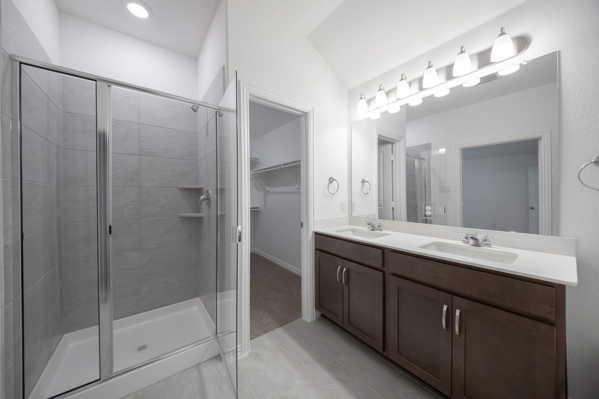 primary bathroom with walk-in shower and dark cabinets