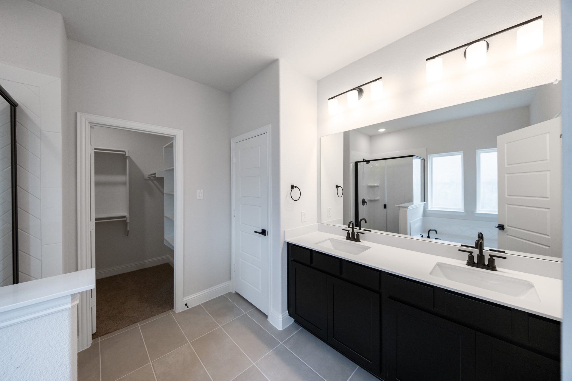 primary bathroom with black cabinets and white countertops 