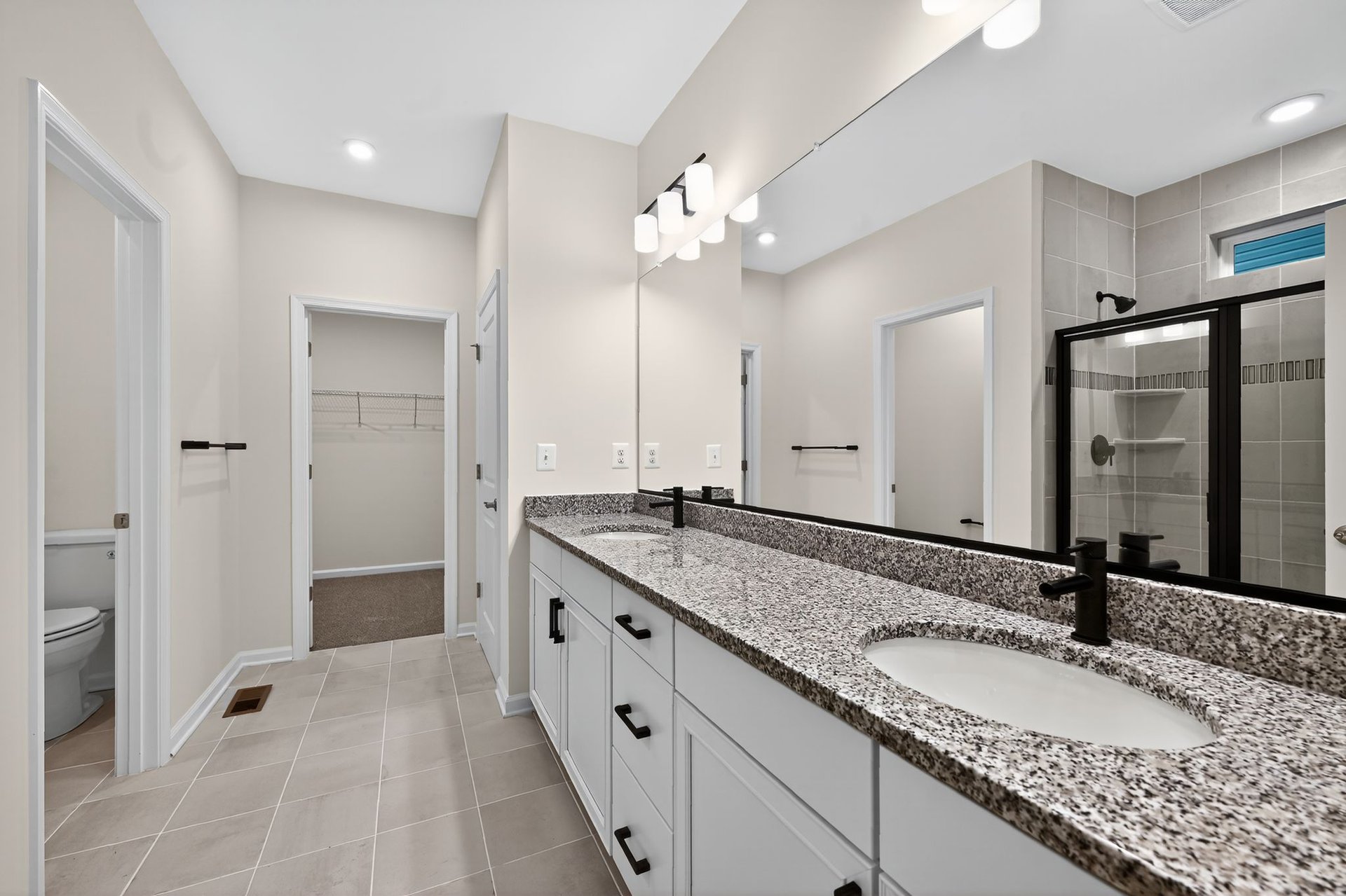 dual vanities in primary bathroom with water closet