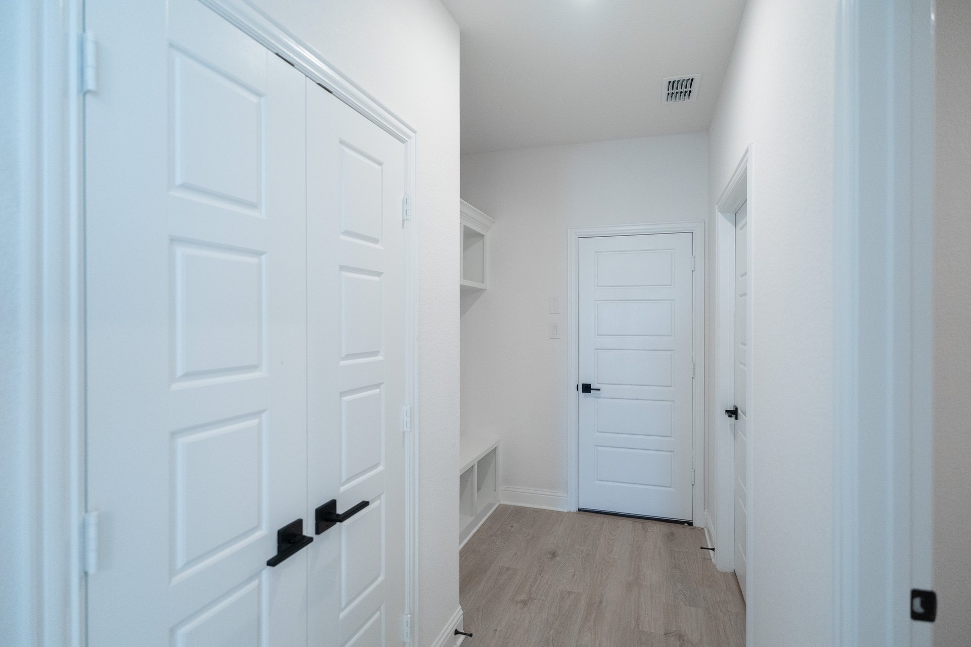 mudroom with wood floors and white shelves with bench