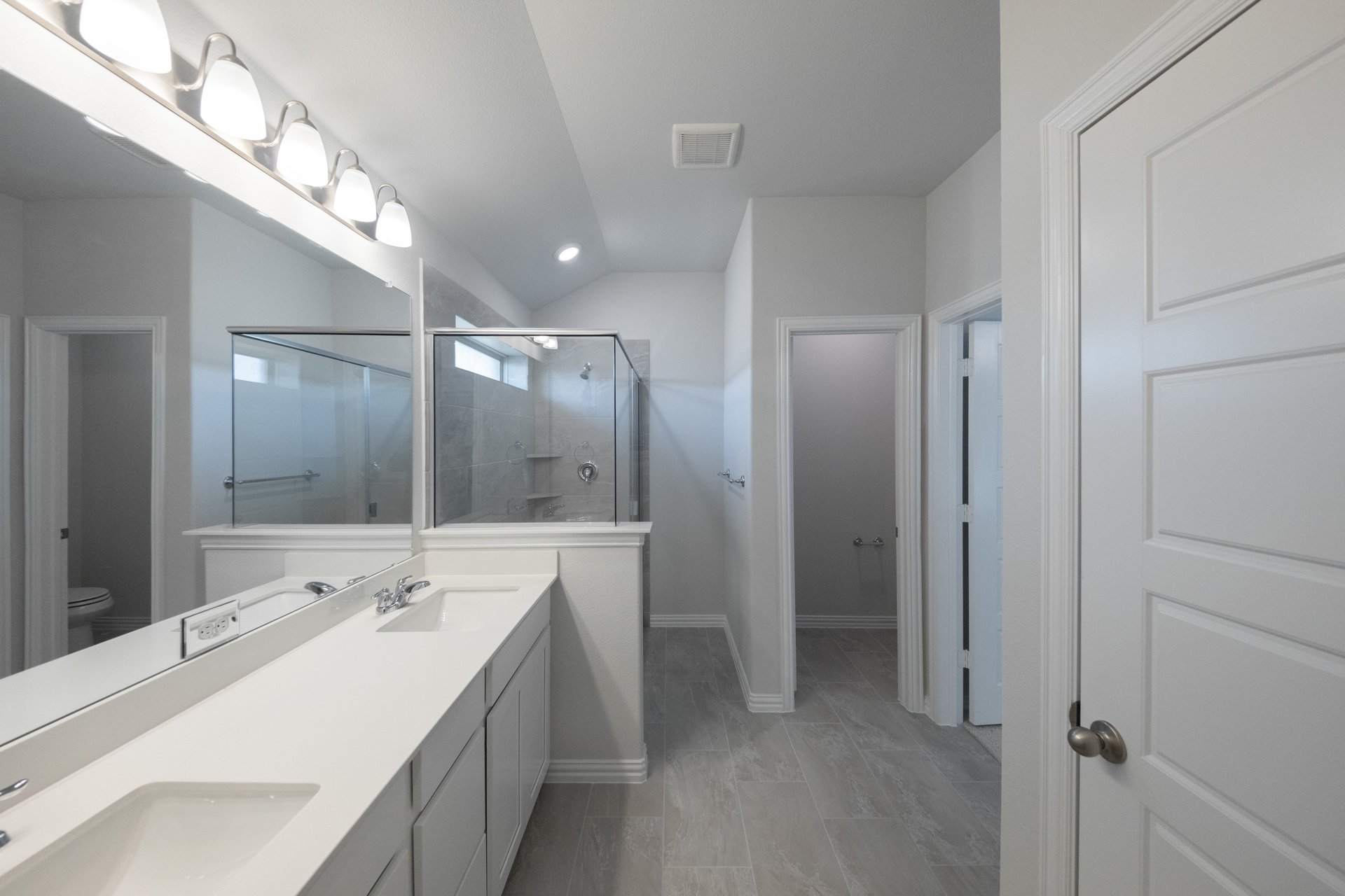 primary bathroom with tile floors and white cabinets
