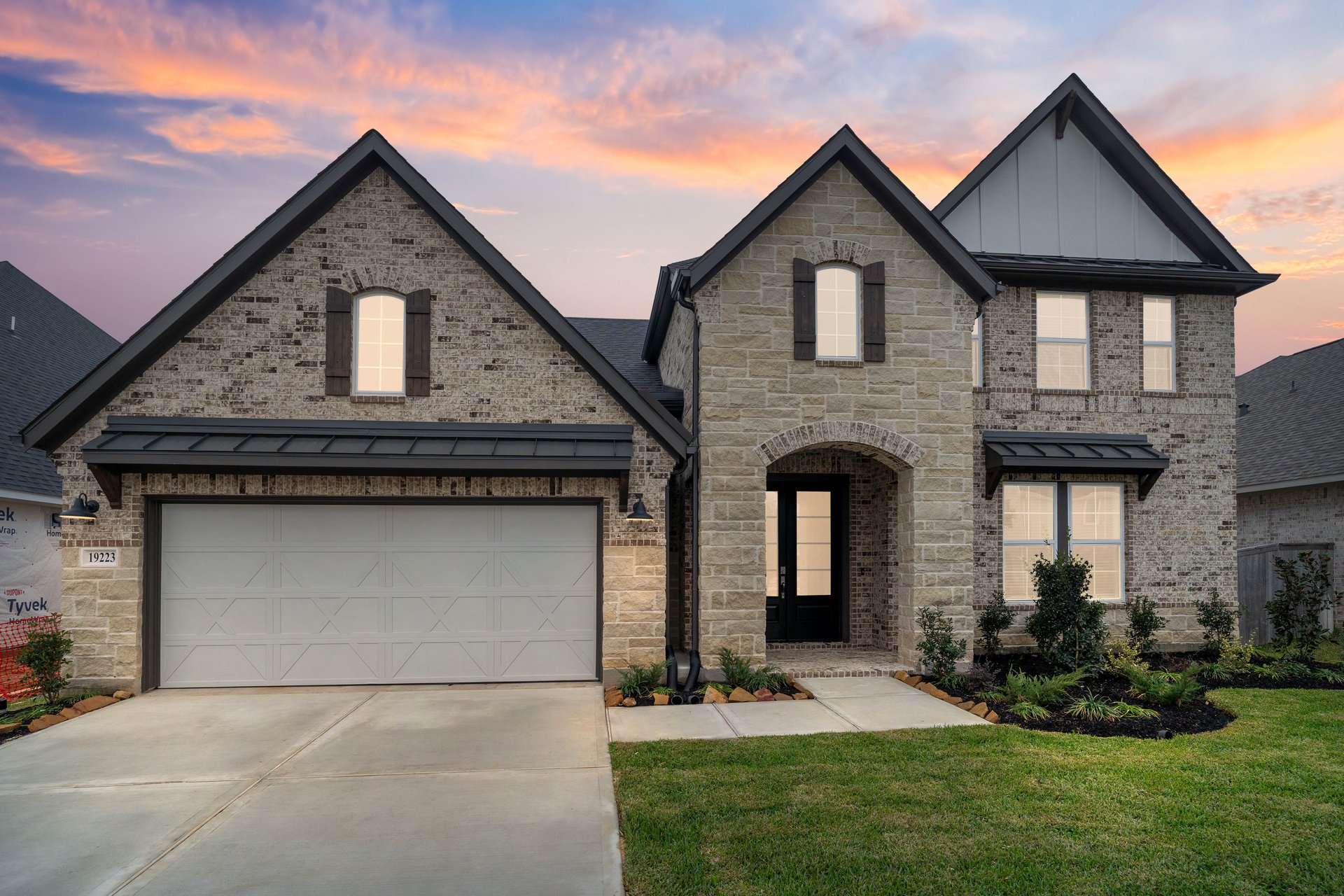 Two-story home with brick and dusk skies. 