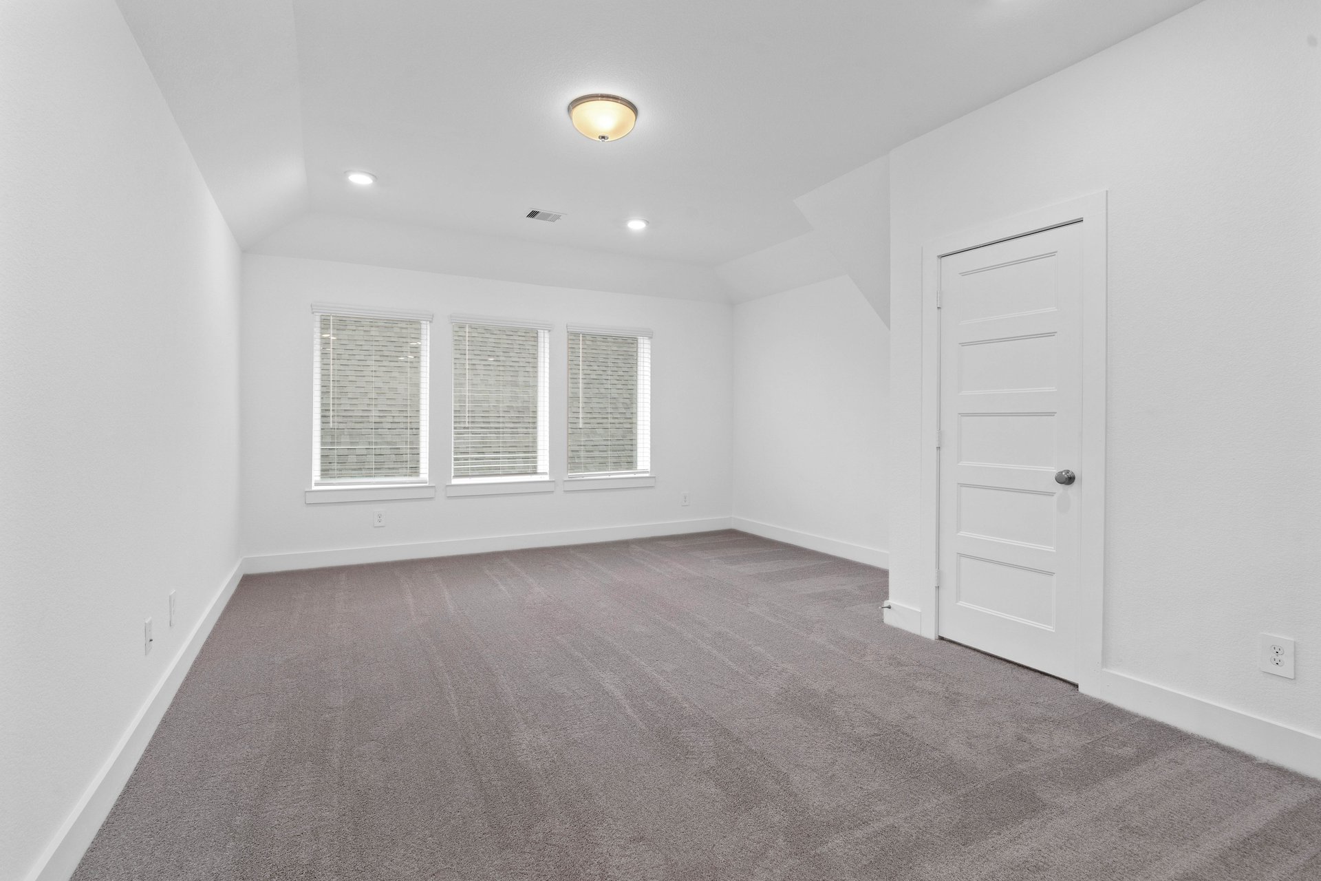 loft with carpet and three windows